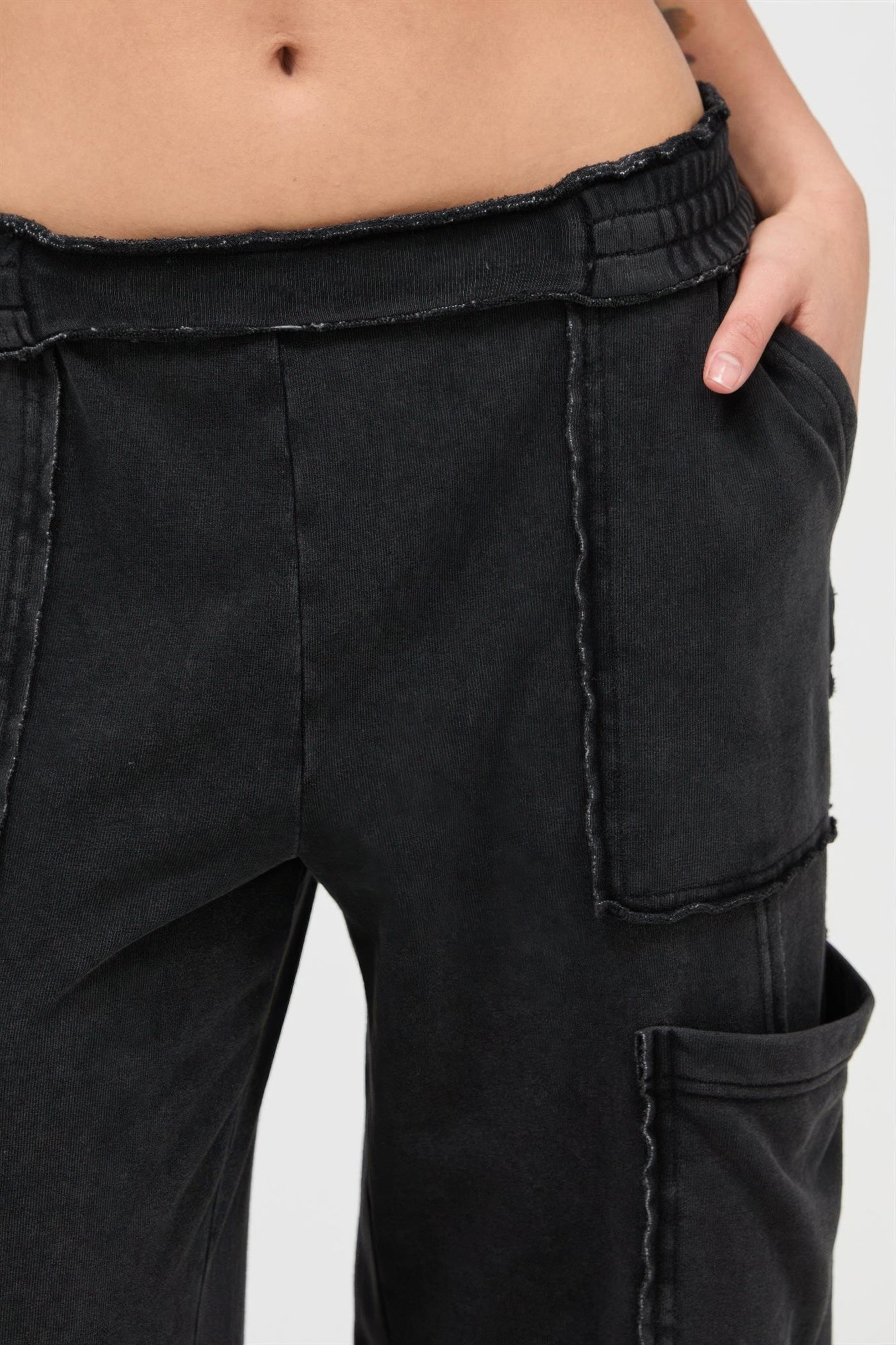Black cargo pants close-up: elastic waistband and stitched pocket details