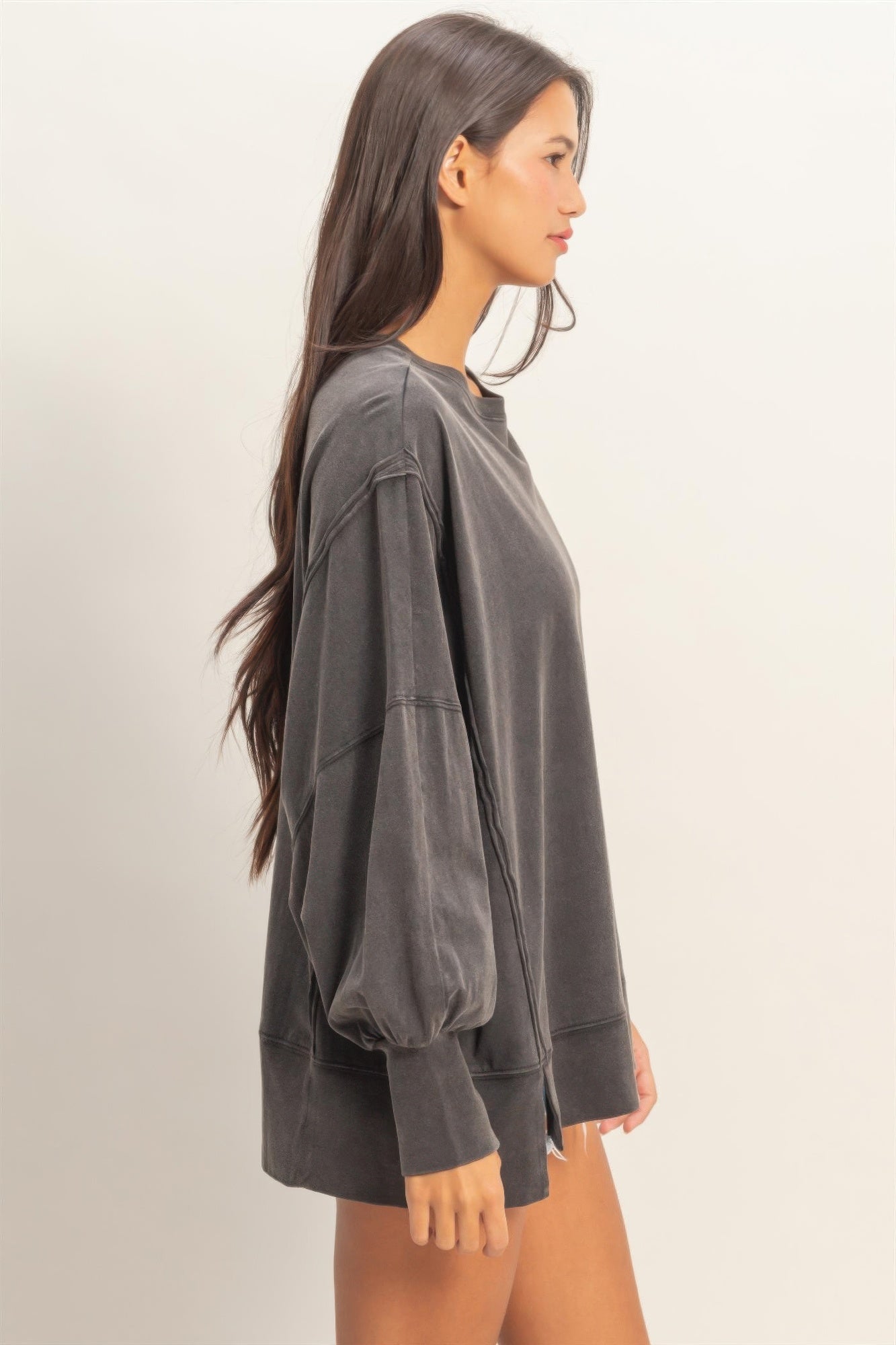 Black oversized long sleeve top from side view, roomy sleeves and seam details