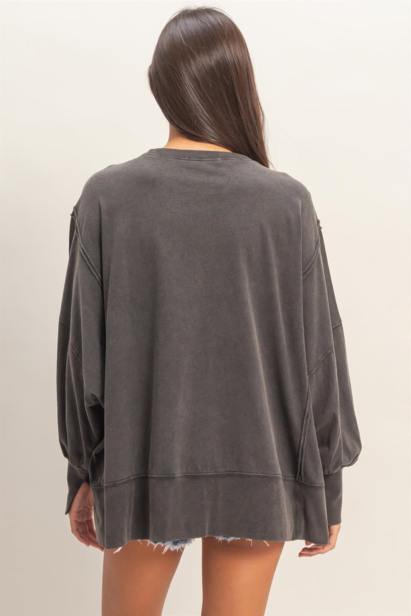 Back view of oversized black long sleeve top with dropped shoulders and seam panels