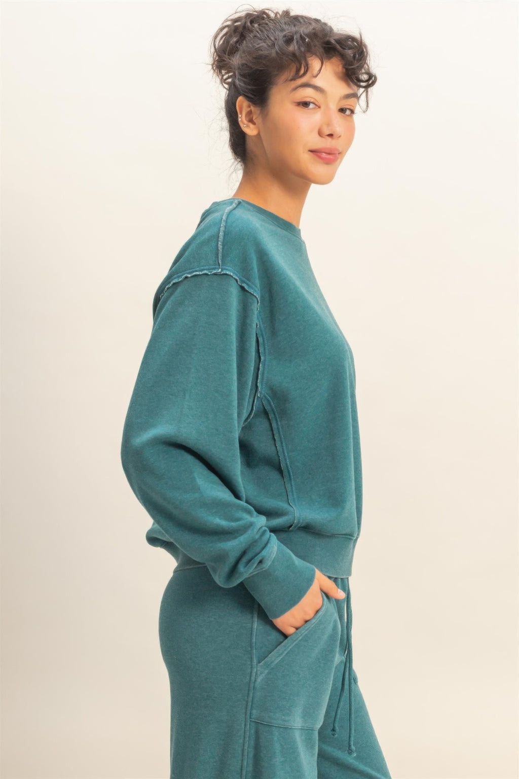 Turquoise raw-edge sweatshirt, side view with dropped sleeves and relaxed shape
