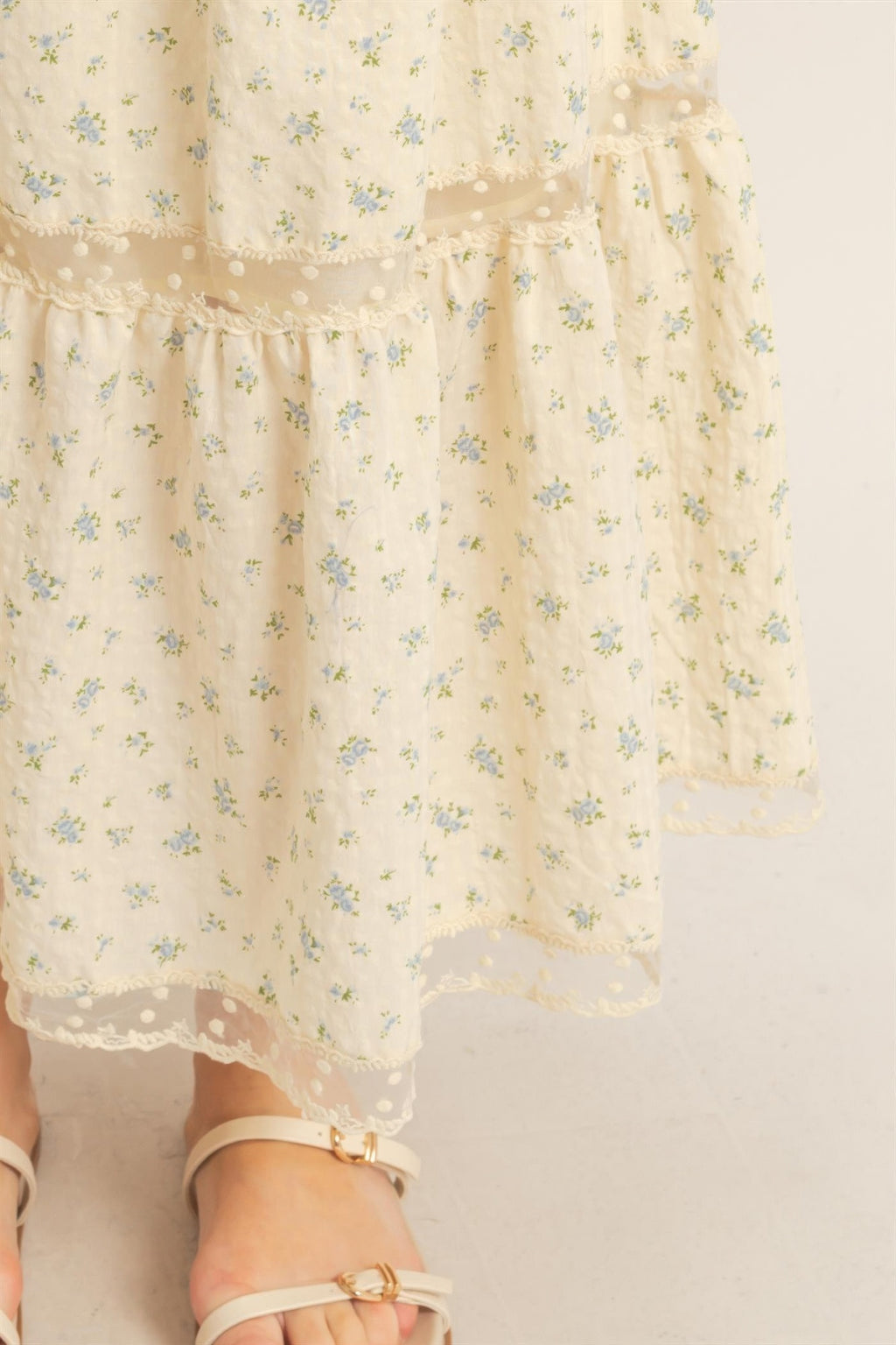 Close-up: cream floral tiered skirt with scalloped lace trim on ruffle layers