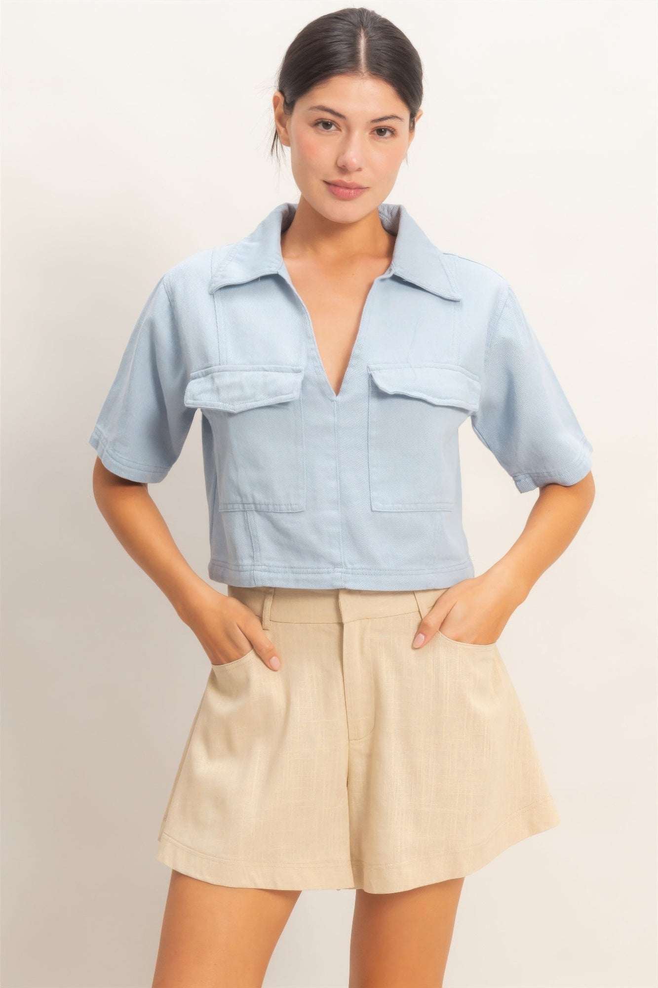Light blue collared V-neck top with short sleeves and chest pockets