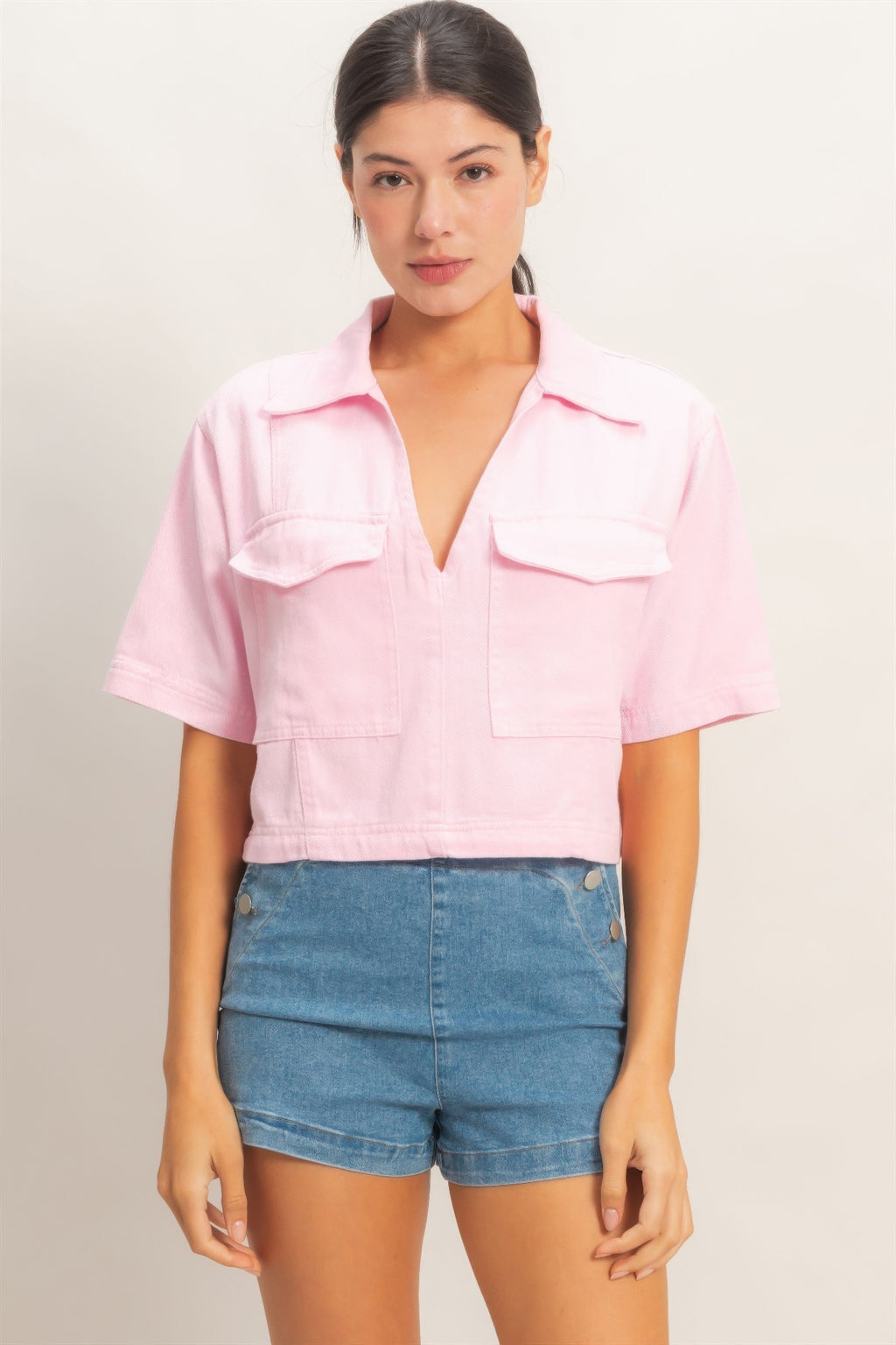 Pink collared V-neck top with chest pockets and short sleeves