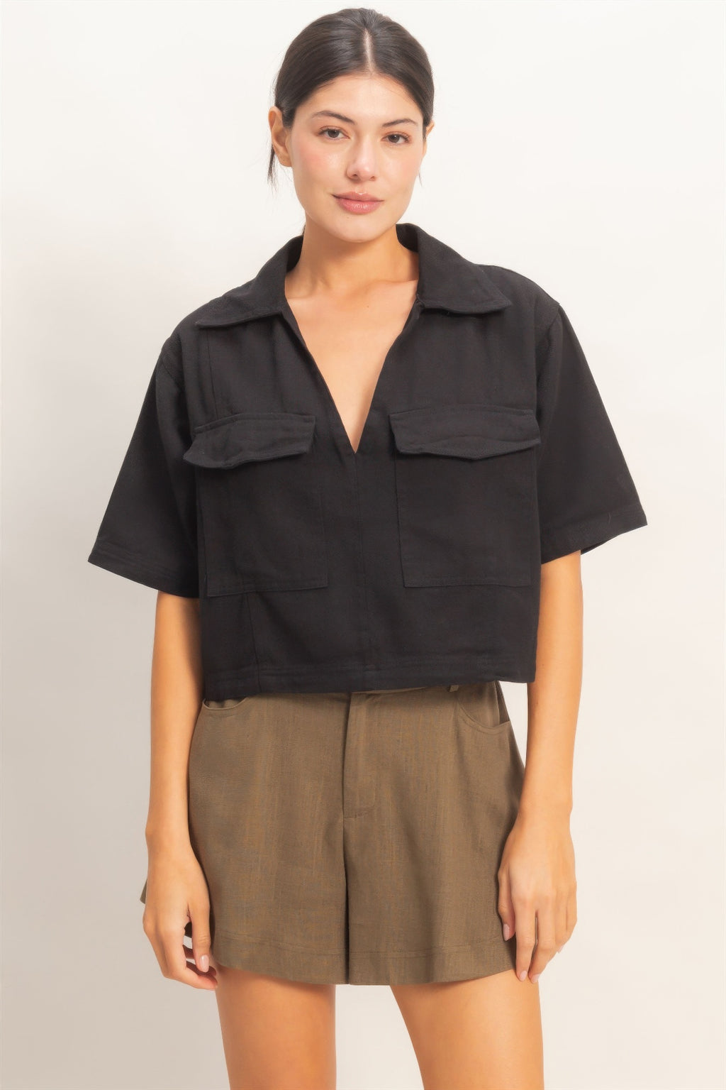 Collared V-neck top in black with chest flap pockets, short sleeves