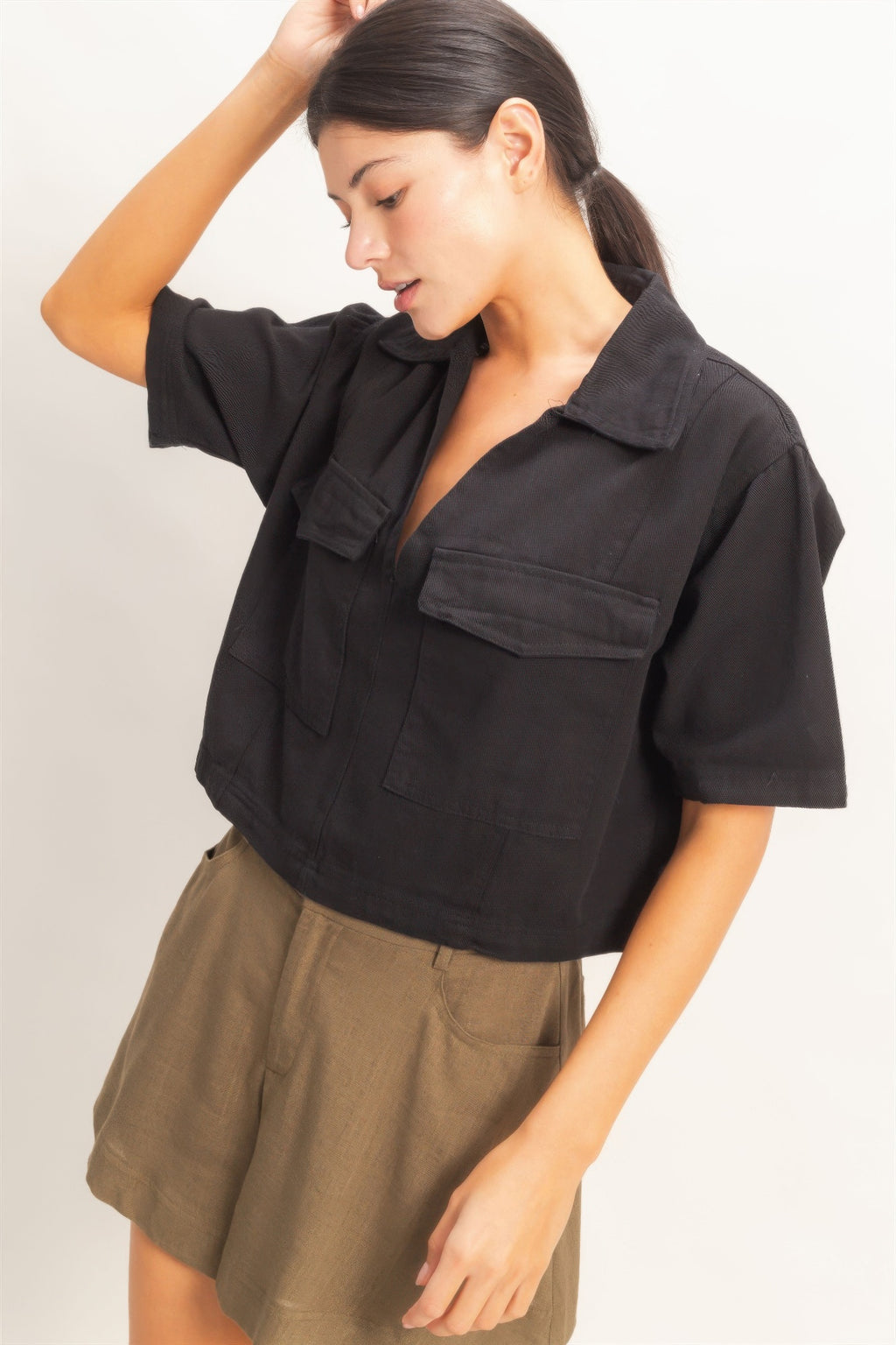 Black collared V-neck top with chest pockets and short sleeves