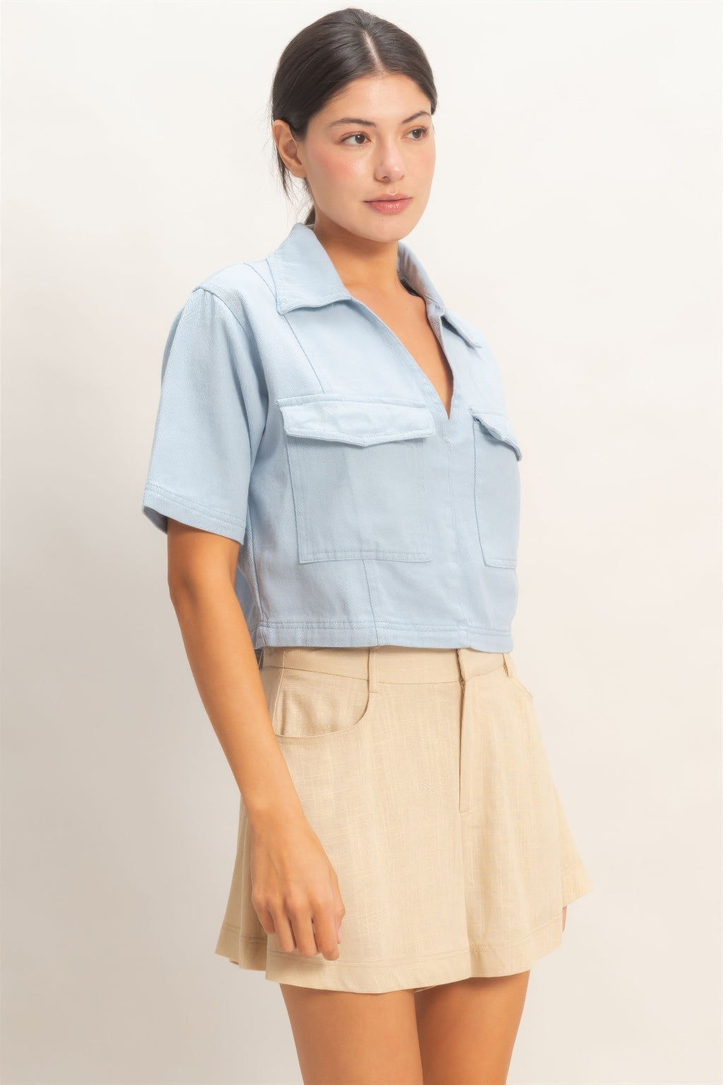 Light blue collared V-neck top with short sleeves and chest patch pocket detail