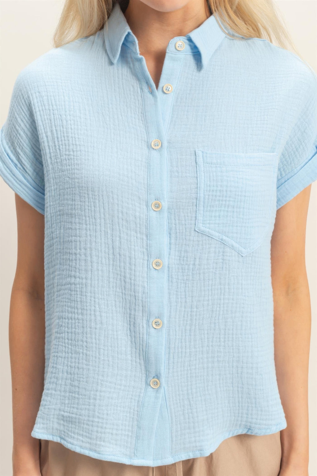 Close-up: light-blue rolled-sleeve button-up top with chest pocket and buttons