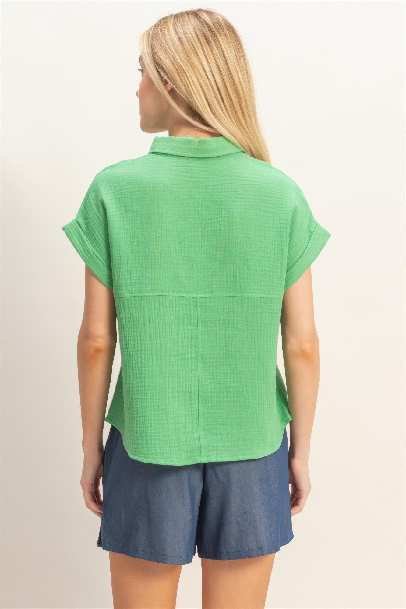 Back view of green rolled-sleeve button-up top with yoke seam