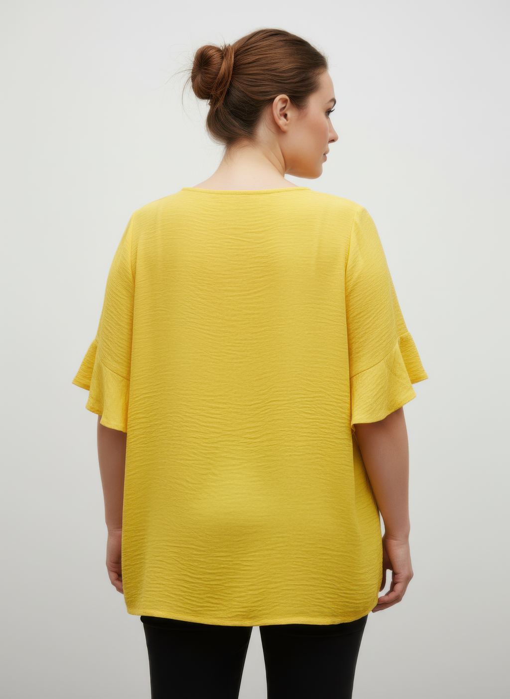 Back view of yellow textured short sleeve top with ruffle cuffs