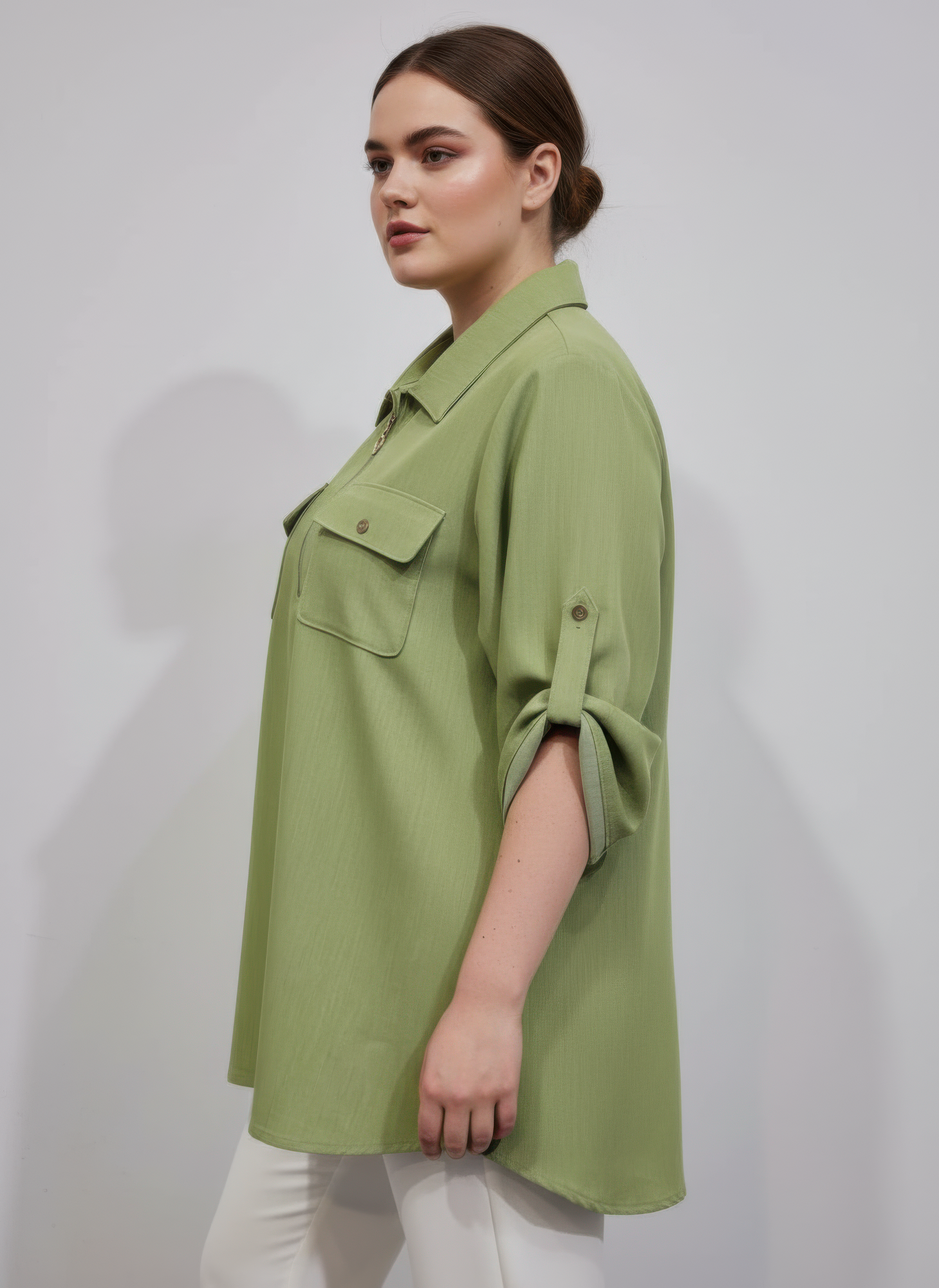 Green zip-front tunic blouse with utility pockets and rolled half sleeves, side view