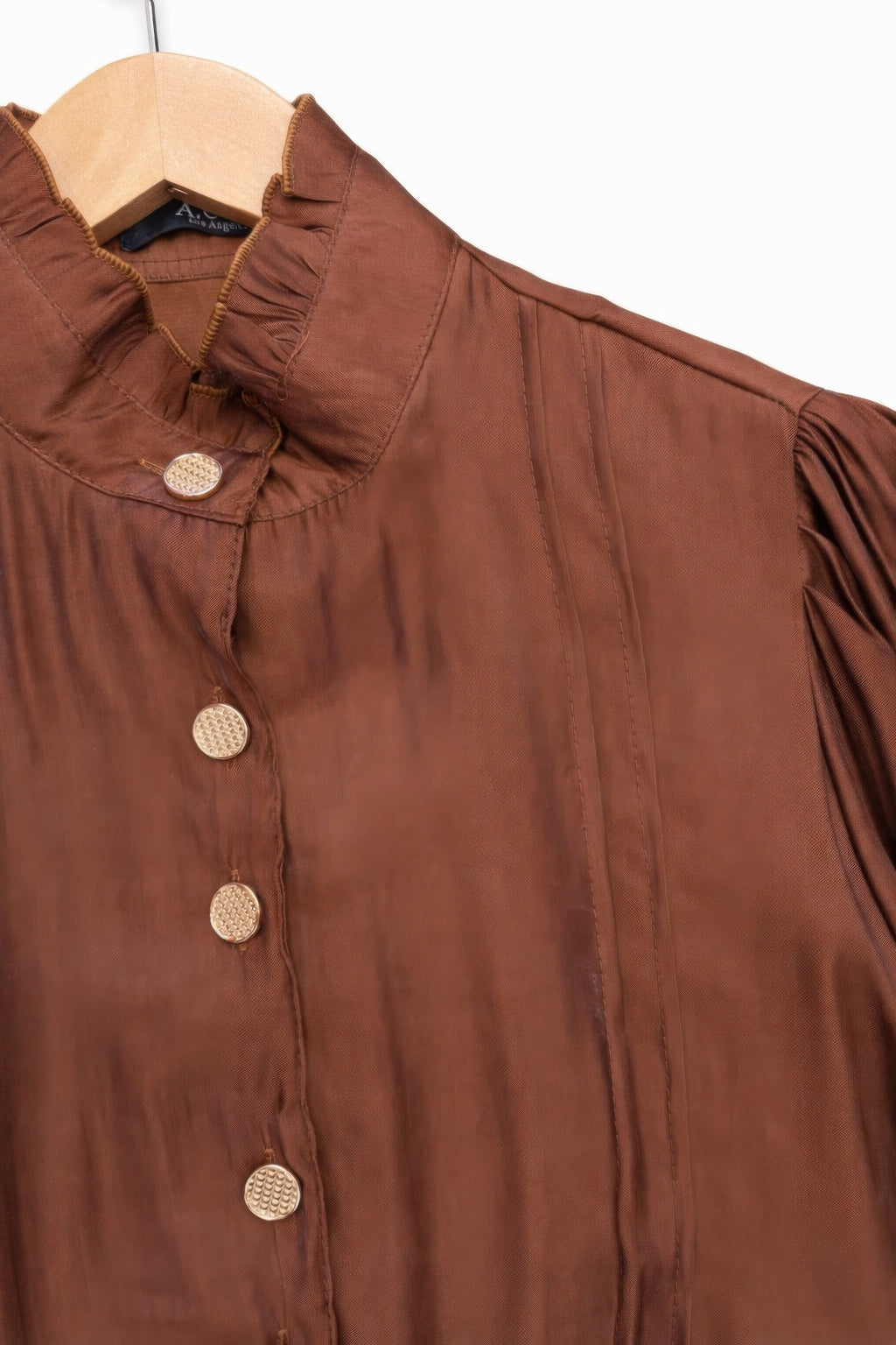 Close-up of brown satin Victorian top: stand collar with textured round buttons, gathered shoulders