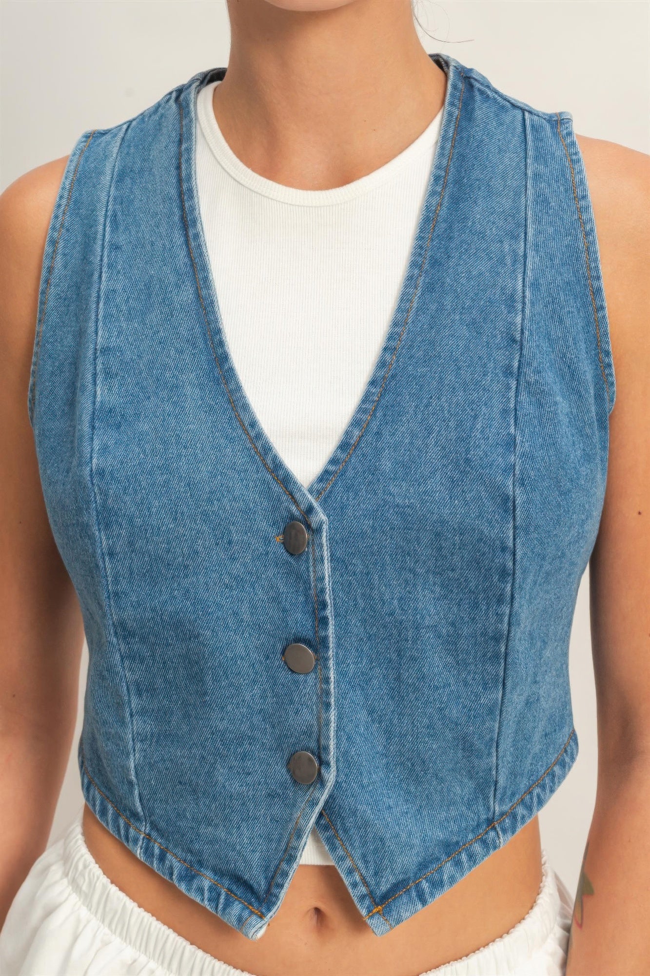 Close-up: light blue sleeveless denim vest V-neck with three dark buttons
