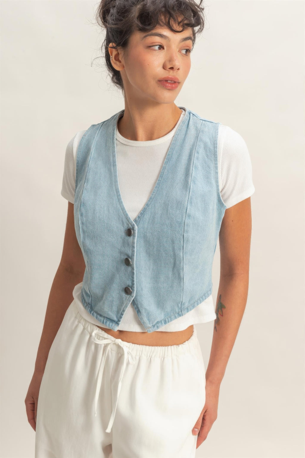 Light blue V-neck sleeveless denim vest with dark buttons and curved hem