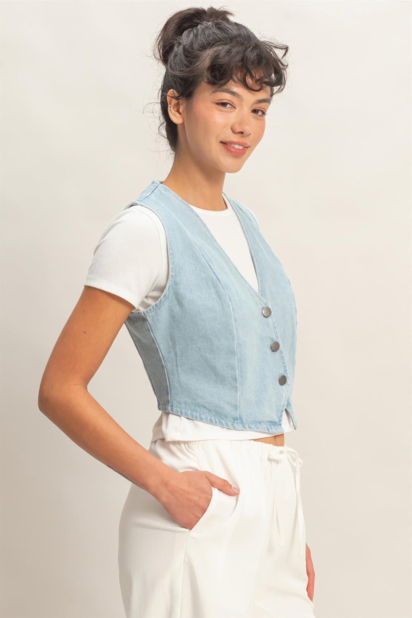 Light blue sleeveless denim vest with V-neck and button closure, angled view