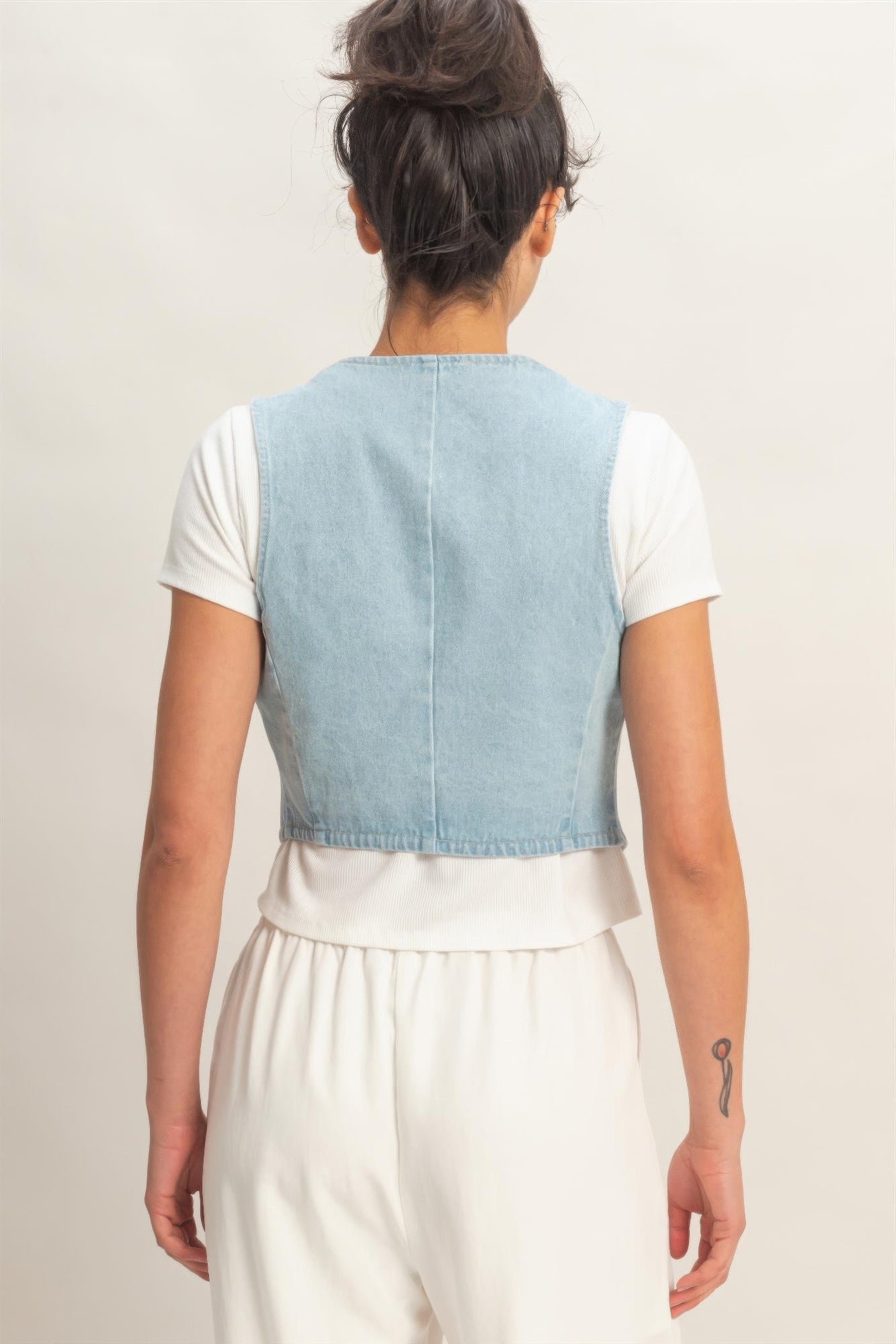 Back view of light blue denim sleeveless V-neck vest with curved hem