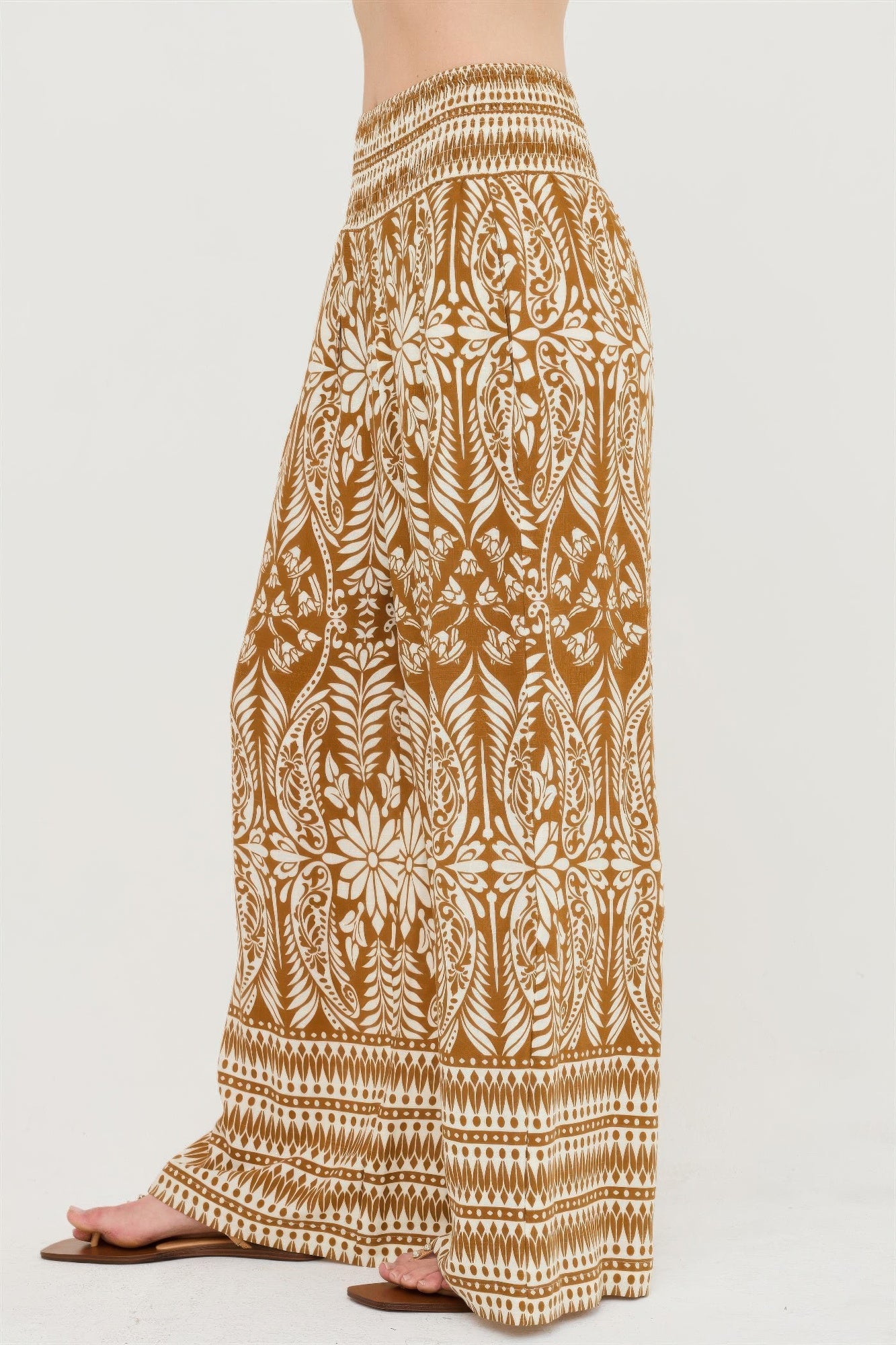 Side view of brown smocked waist floral wide-leg pants with striped cuff border