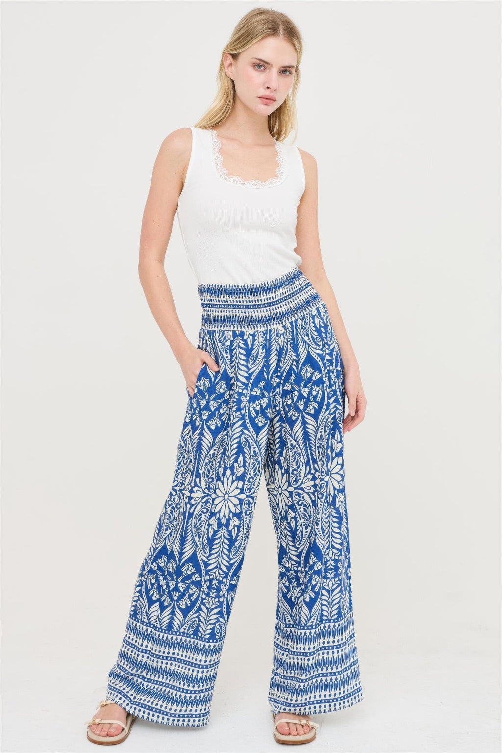 Blue smocked waist floral pants with wide-leg silhouette and white botanical motif