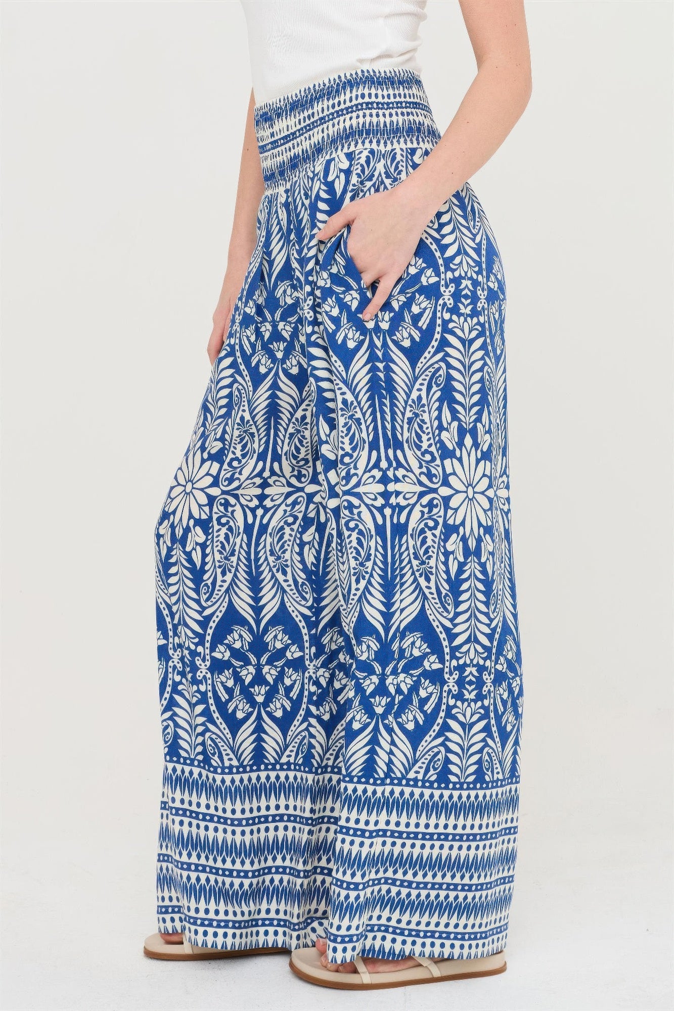 Side view of blue smocked waist floral pants with detailed white leaf print