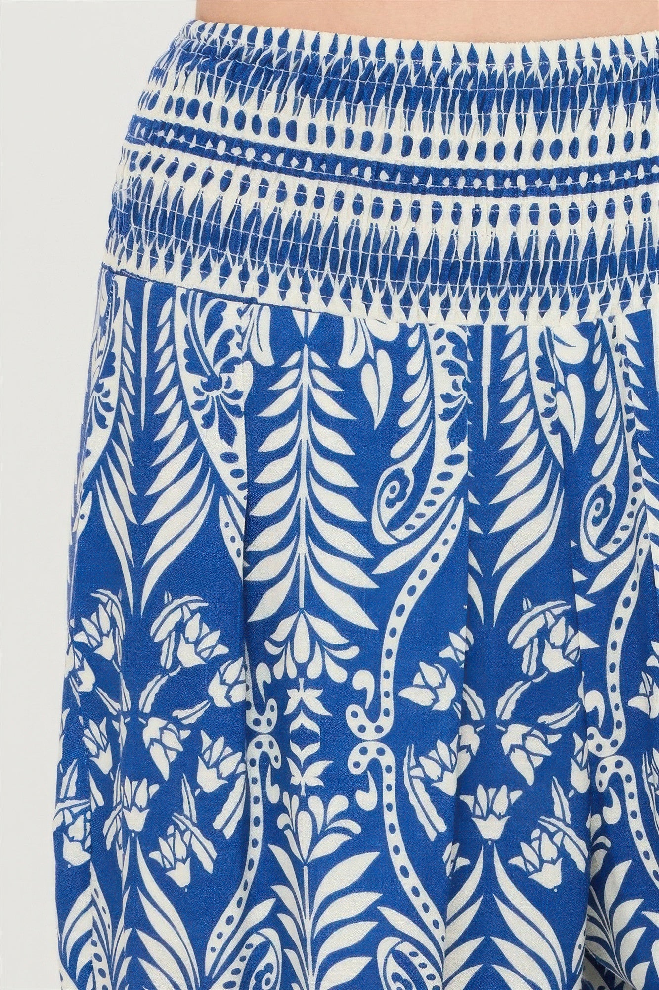 Close-up of blue smocked waistband and white ornate floral pattern