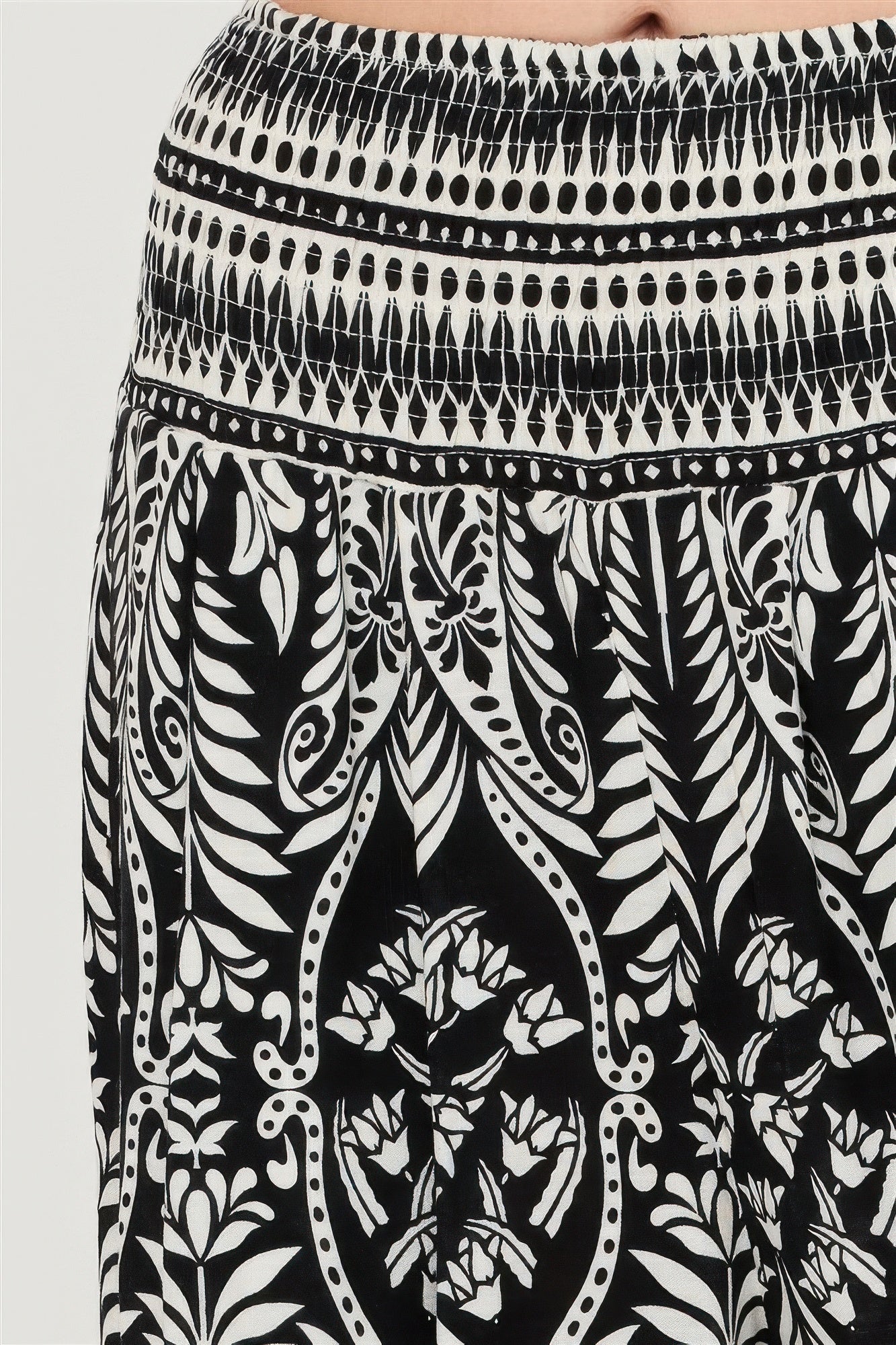 Close-up of smocked waistband and black floral border print on pants