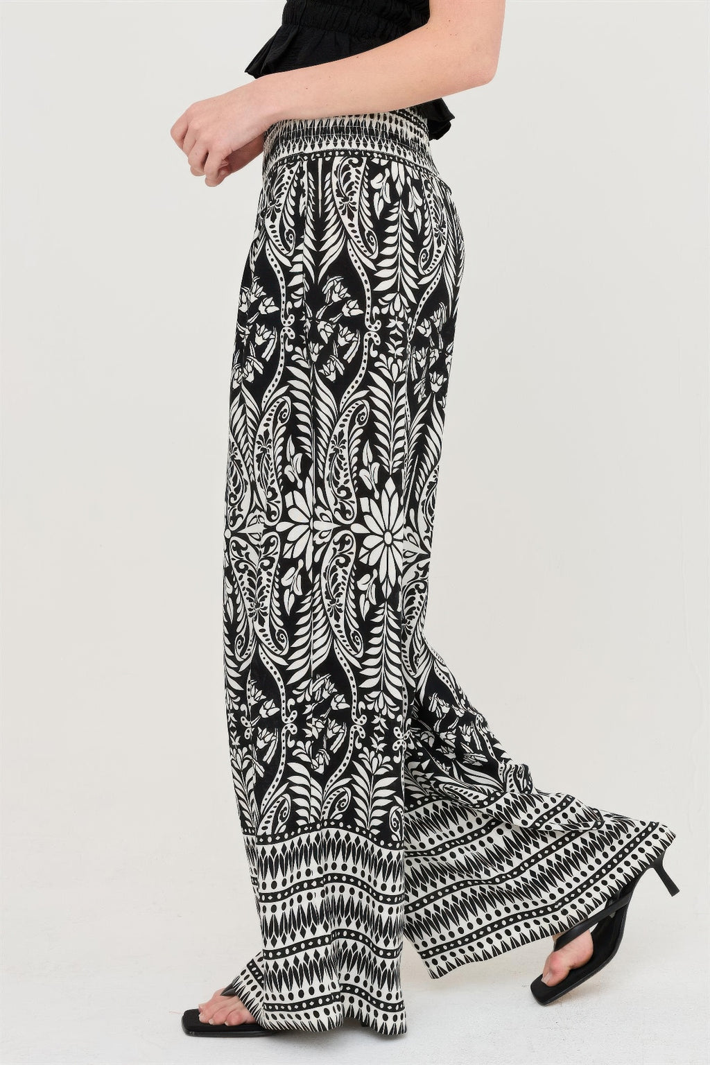 Black-and-white smocked waist floral pants, side view with flowing wide legs