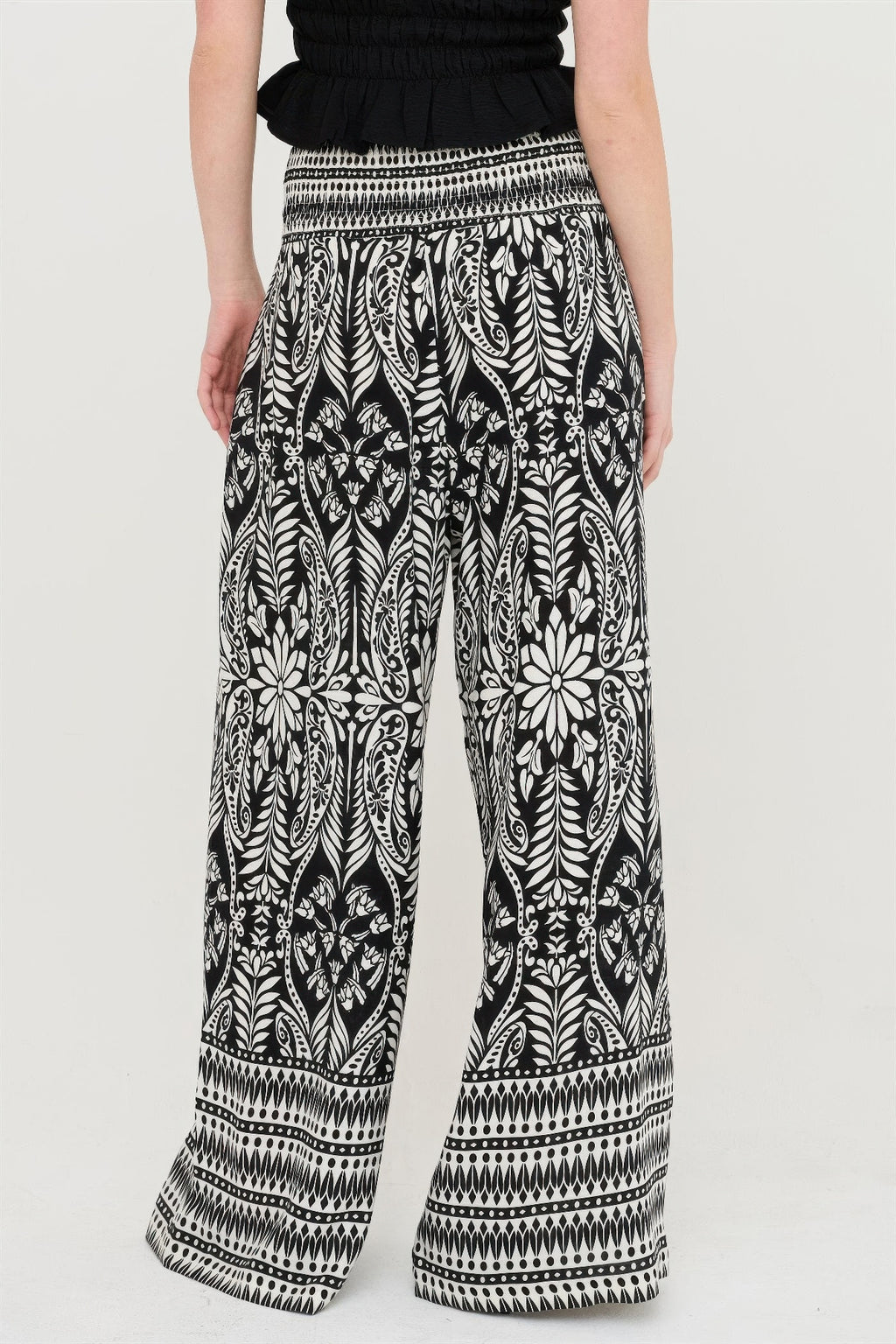 Back view of black smocked waist floral pants with all-over botanical print
