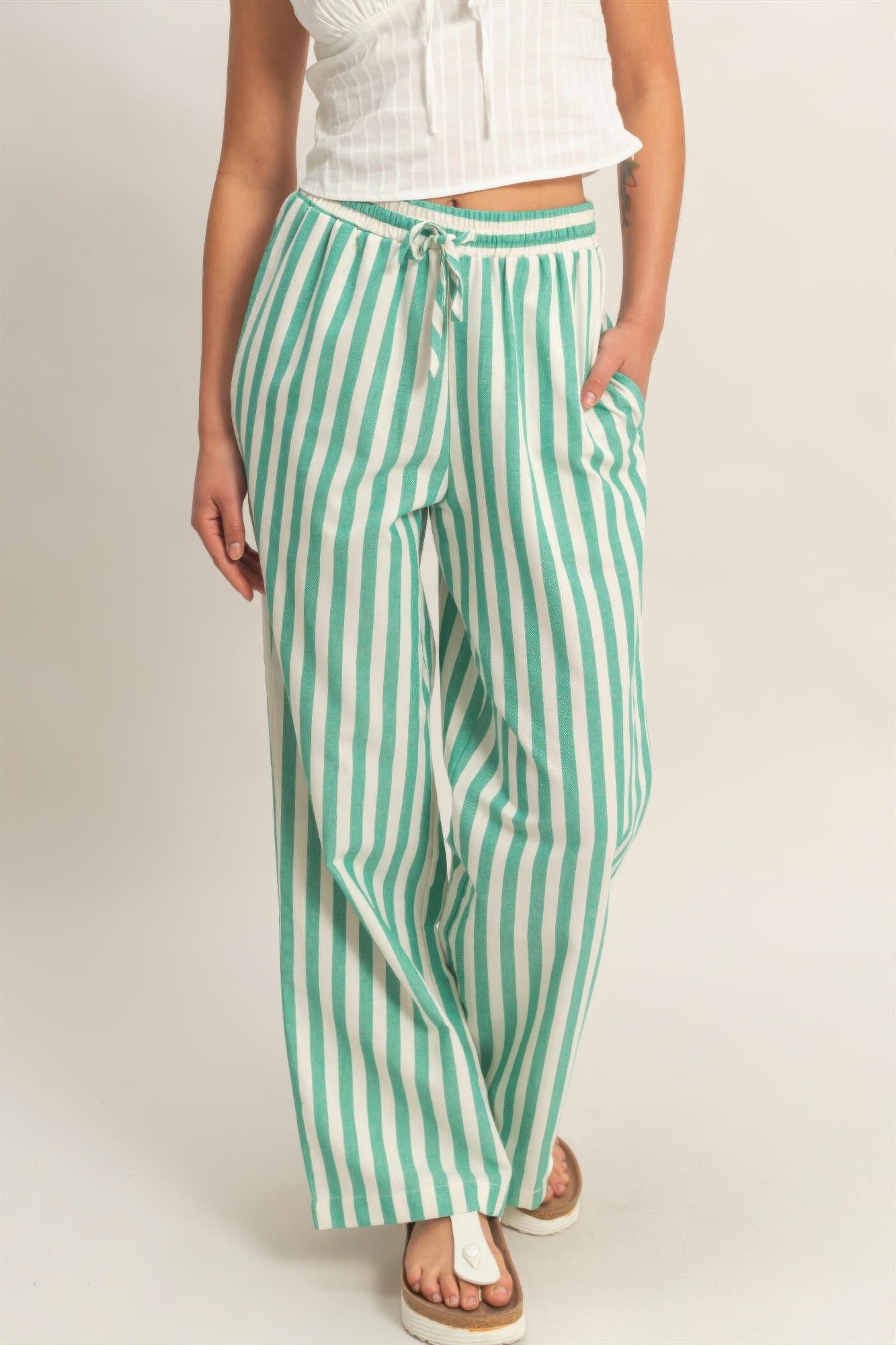 Green-and-white vertical striped pants with elastic waist, drawstring, and side pockets