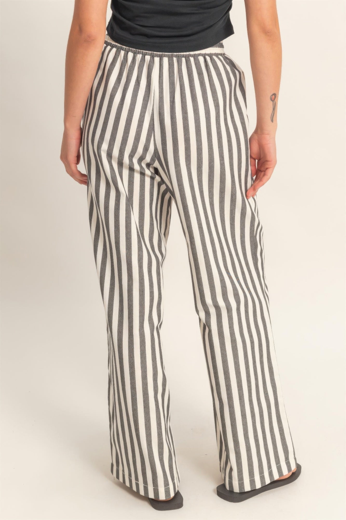 Black-and-white vertical striped elastic pants with side pockets and drawstring waist