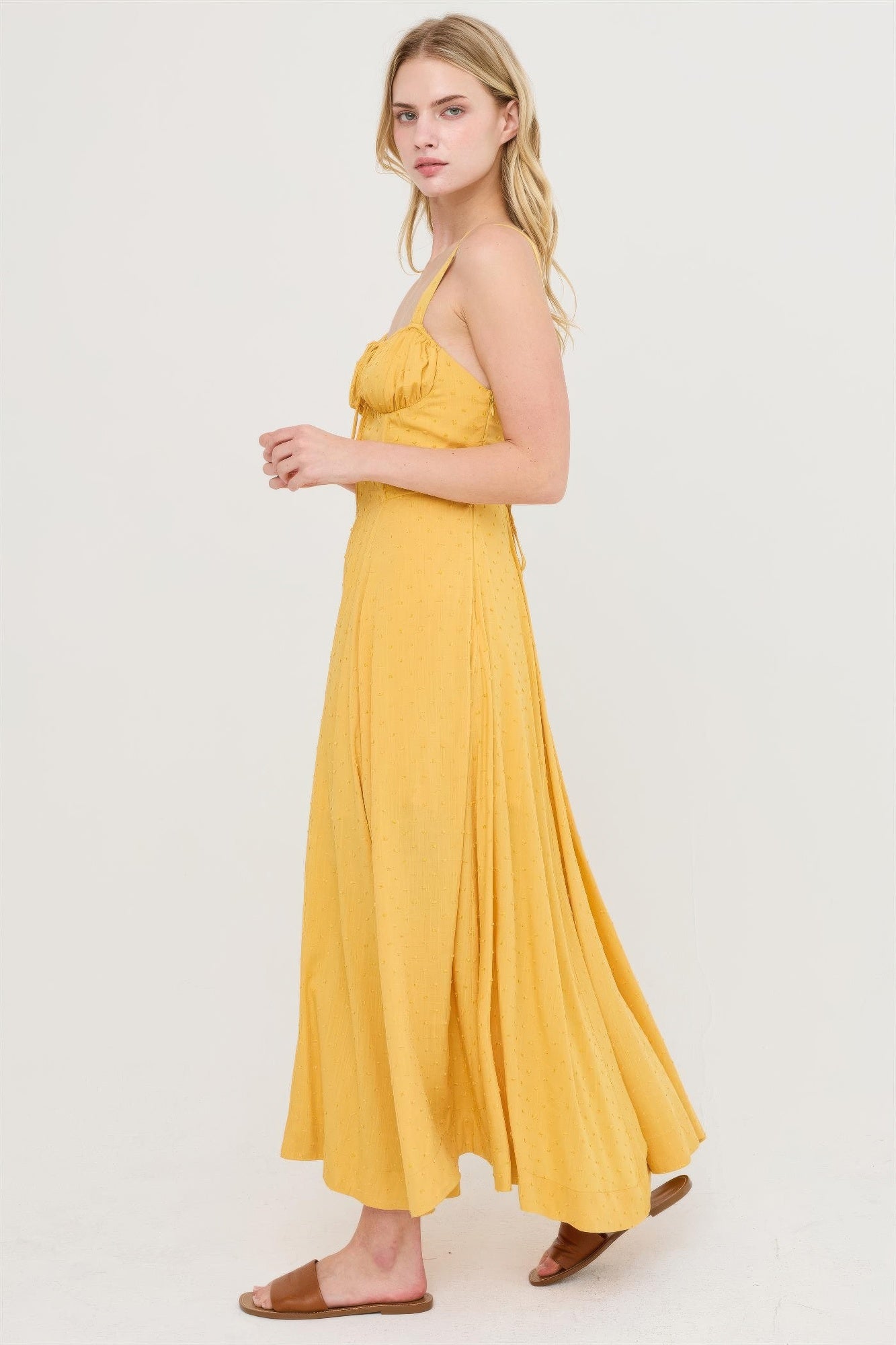 Mustard yellow sleeveless tie-back dress with gathered bust and flowing midi hem.