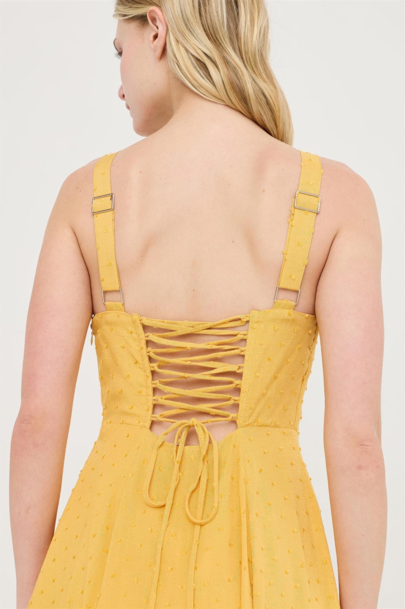 Mustard yellow open-back dress with crisscross lacing and tie waist detail.