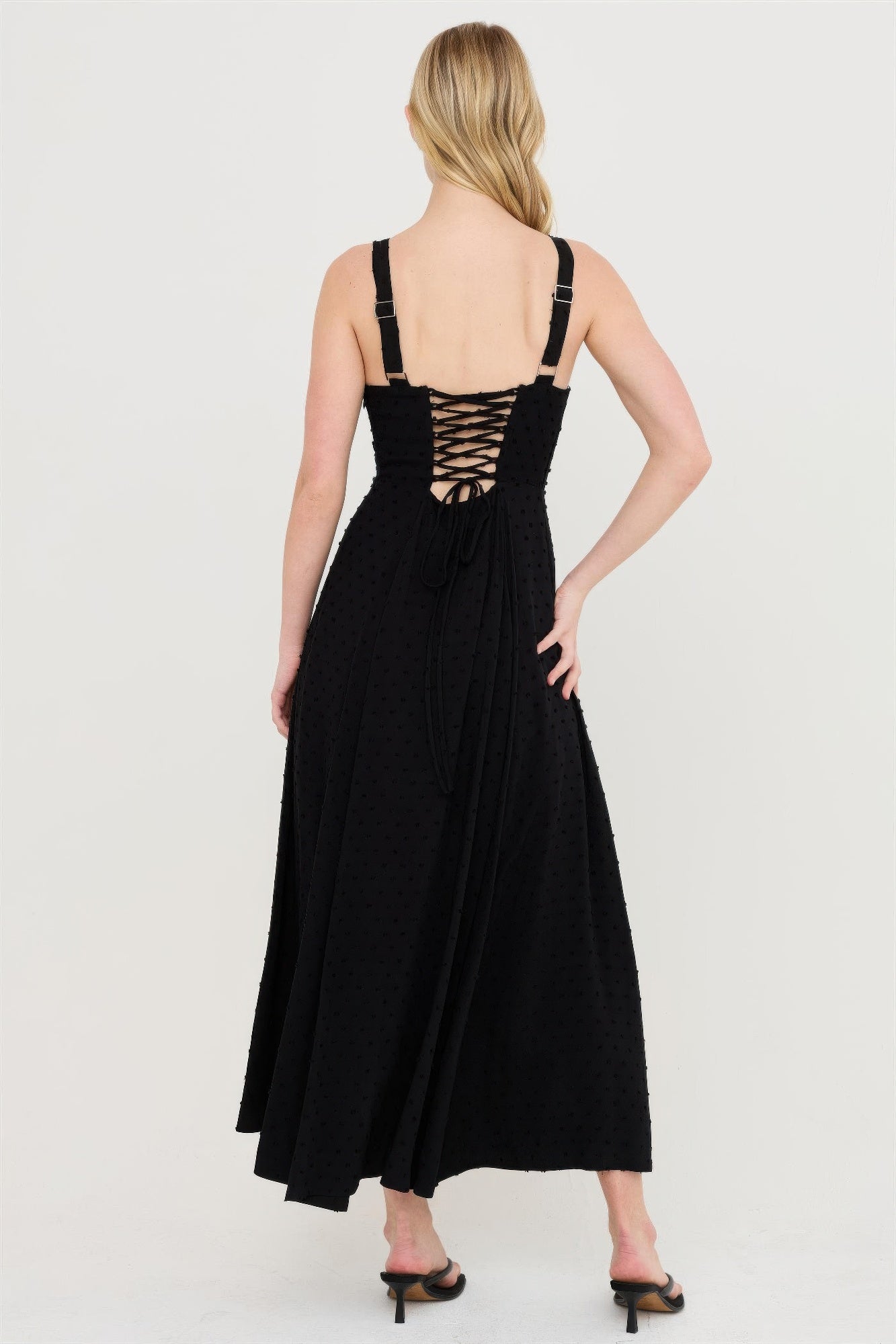 Back view of black tie-back dress with crisscross lacing and midi skirt.
