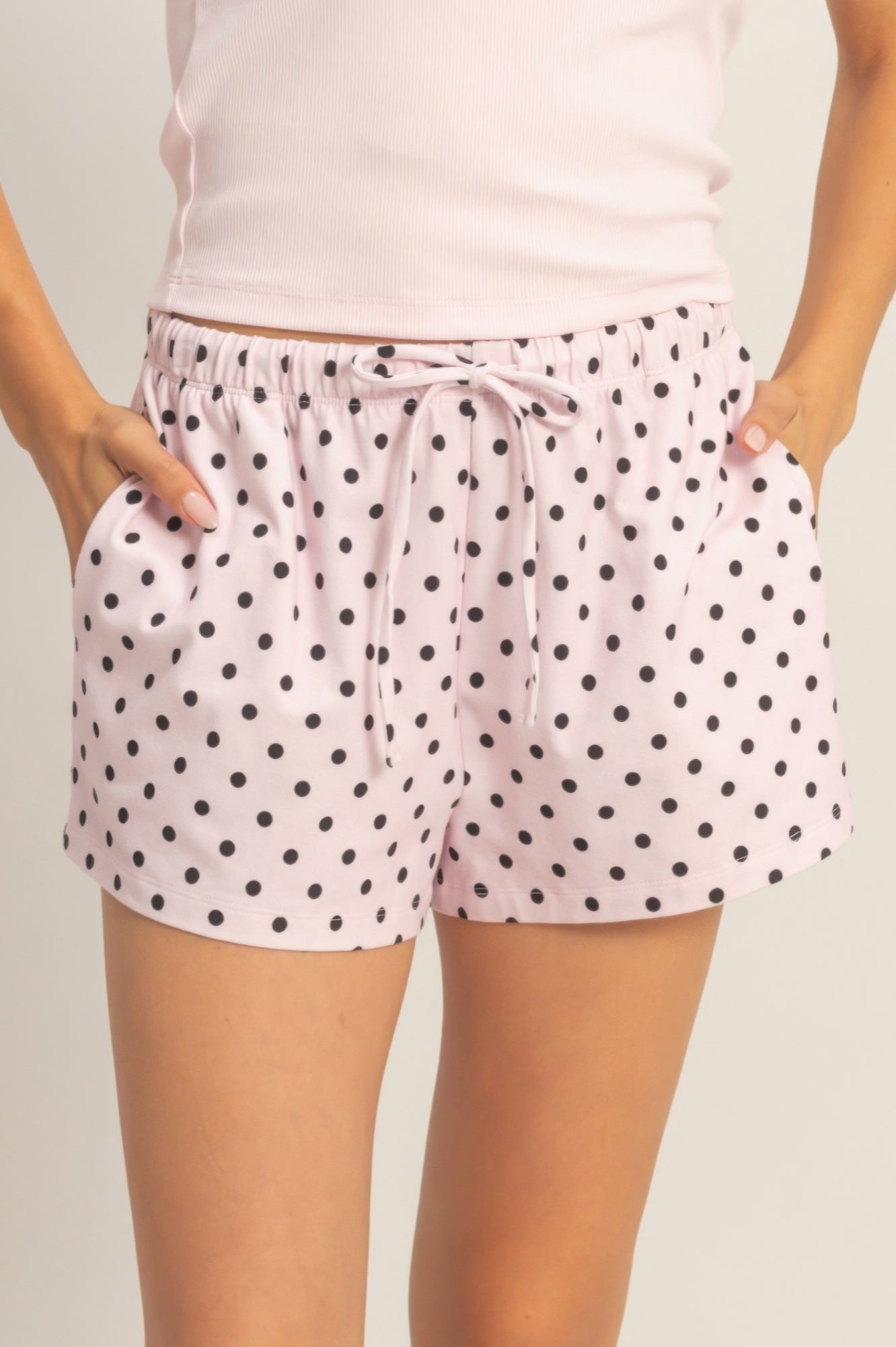 Polka dot drawstring shorts, light fabric with black dots and tie waist detail.