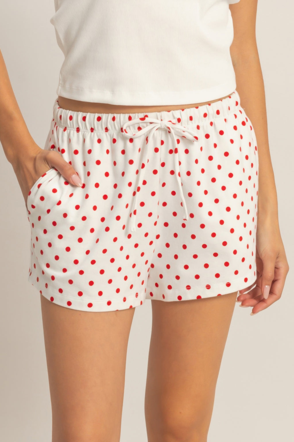 White polka dot drawstring shorts with red dots and tied elastic waist.