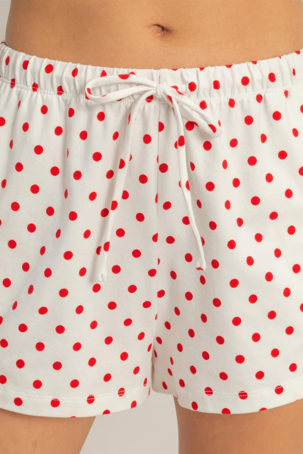 White polka dot drawstring shorts with red dots, elastic waistband and bow tie