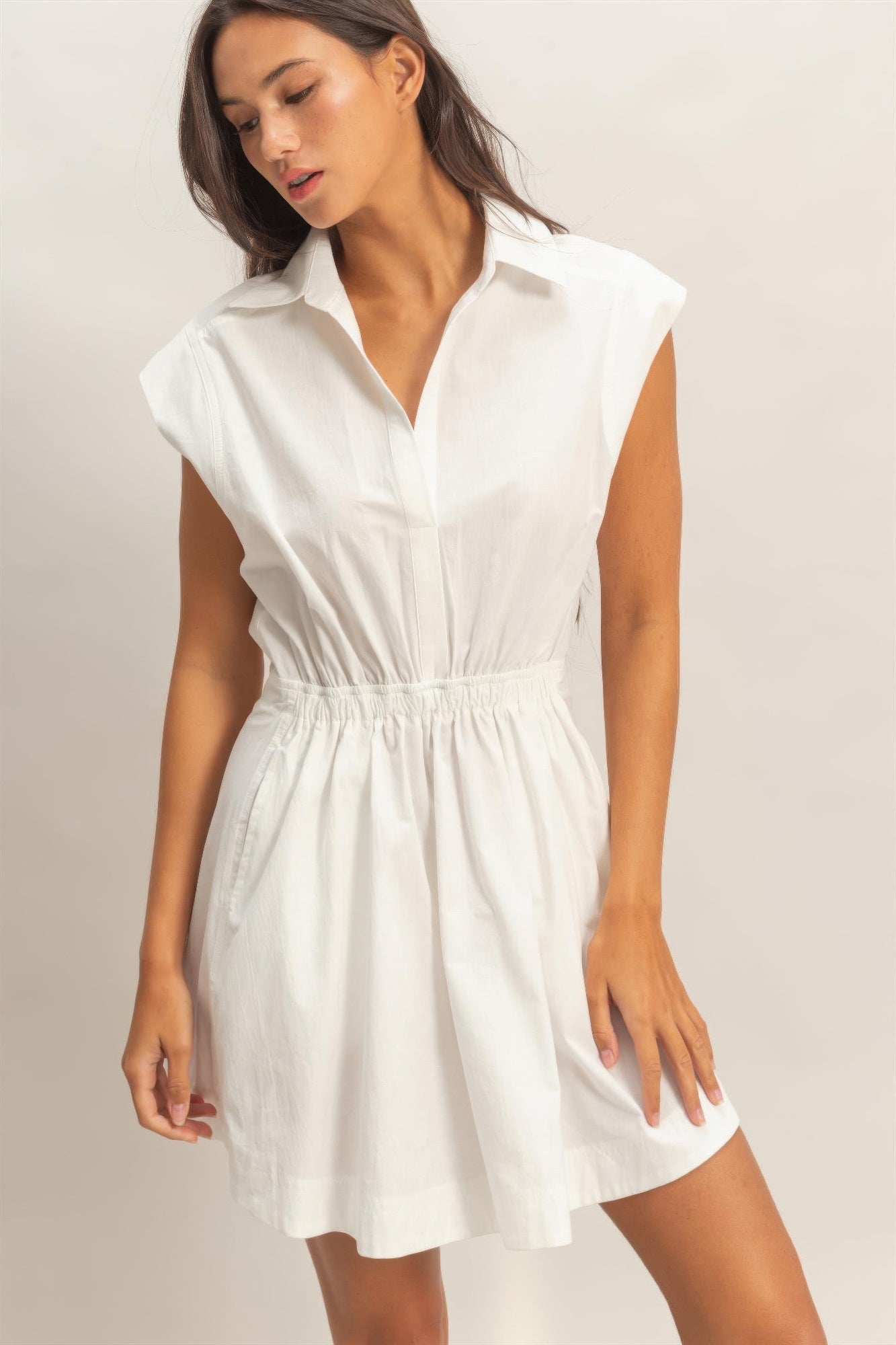 White sleeveless collared mini dress with button front and shirred waist