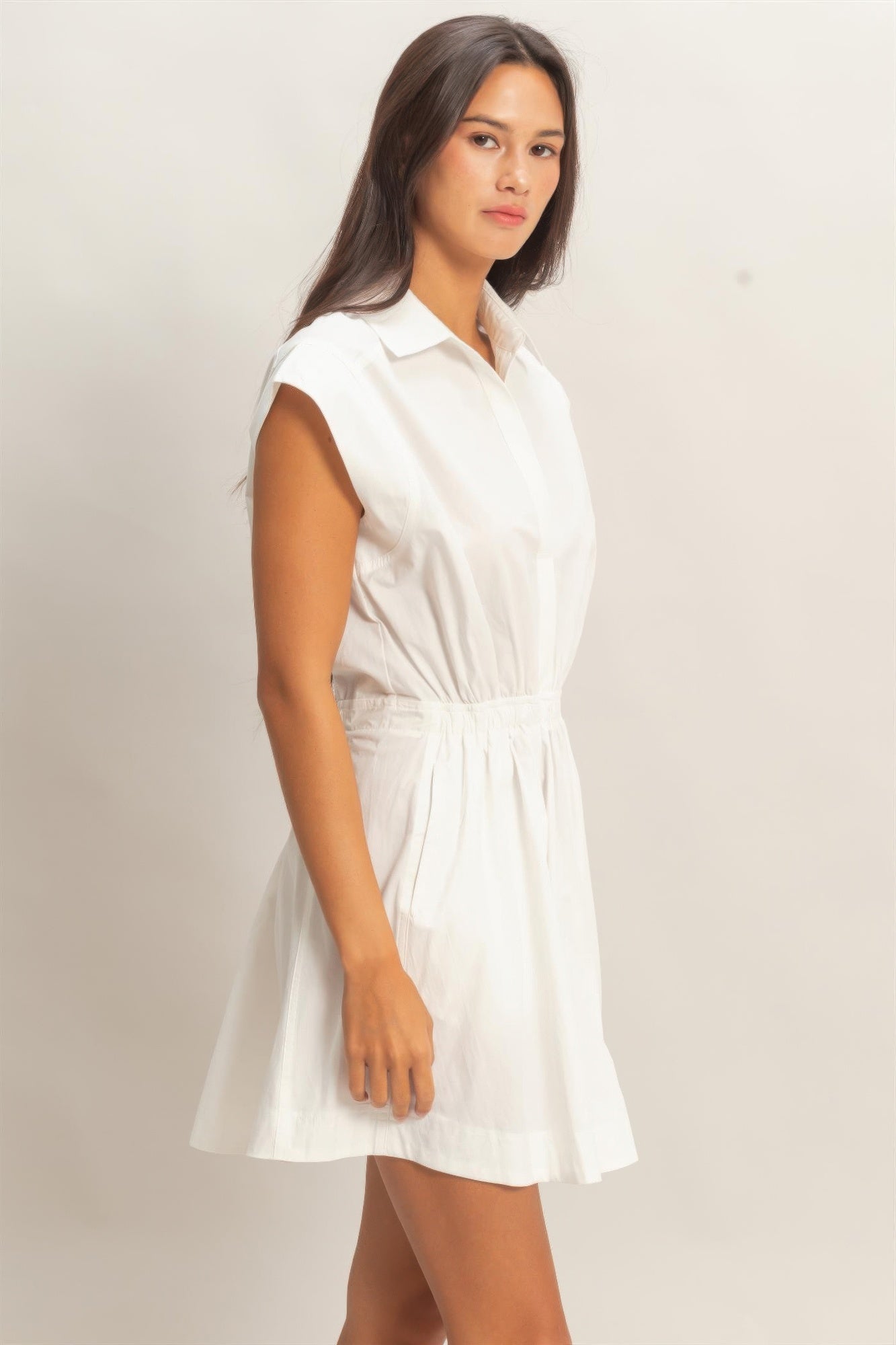 White sleeveless collared mini dress with gathered waist, angled front