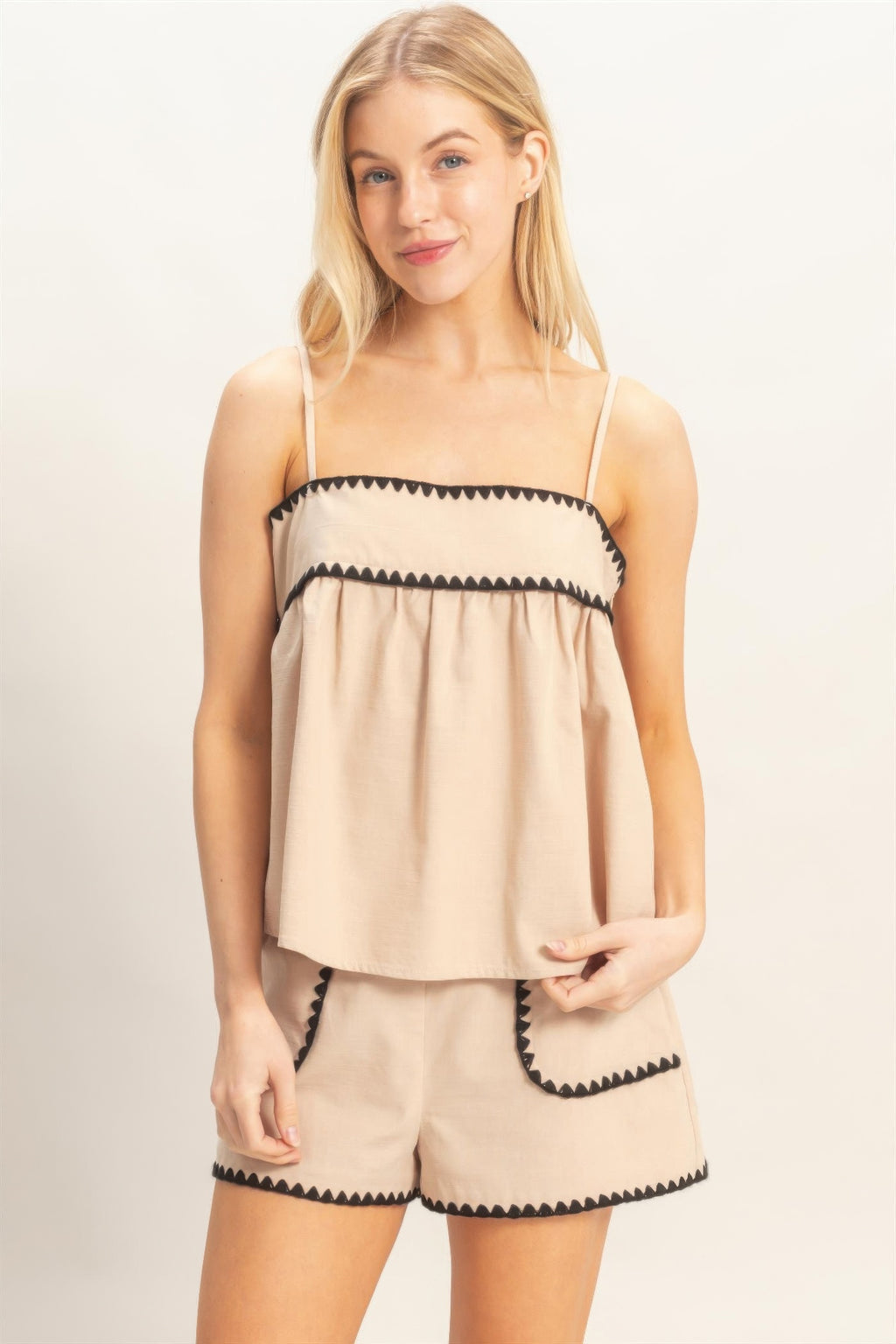 Sleeveless beige babydoll top with scalloped black trim and spaghetti straps
