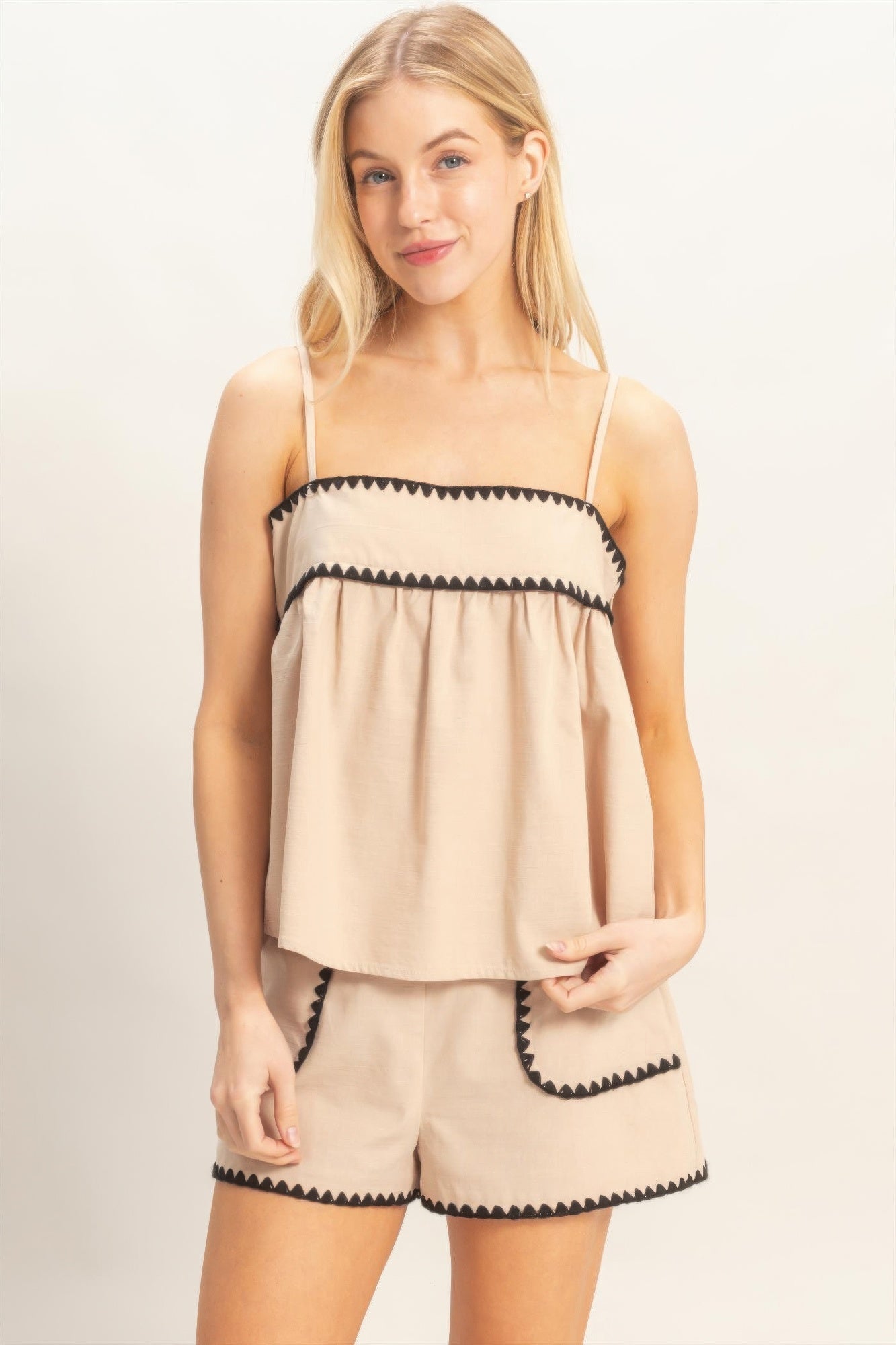 Sleeveless beige babydoll top with scalloped black trim and spaghetti straps