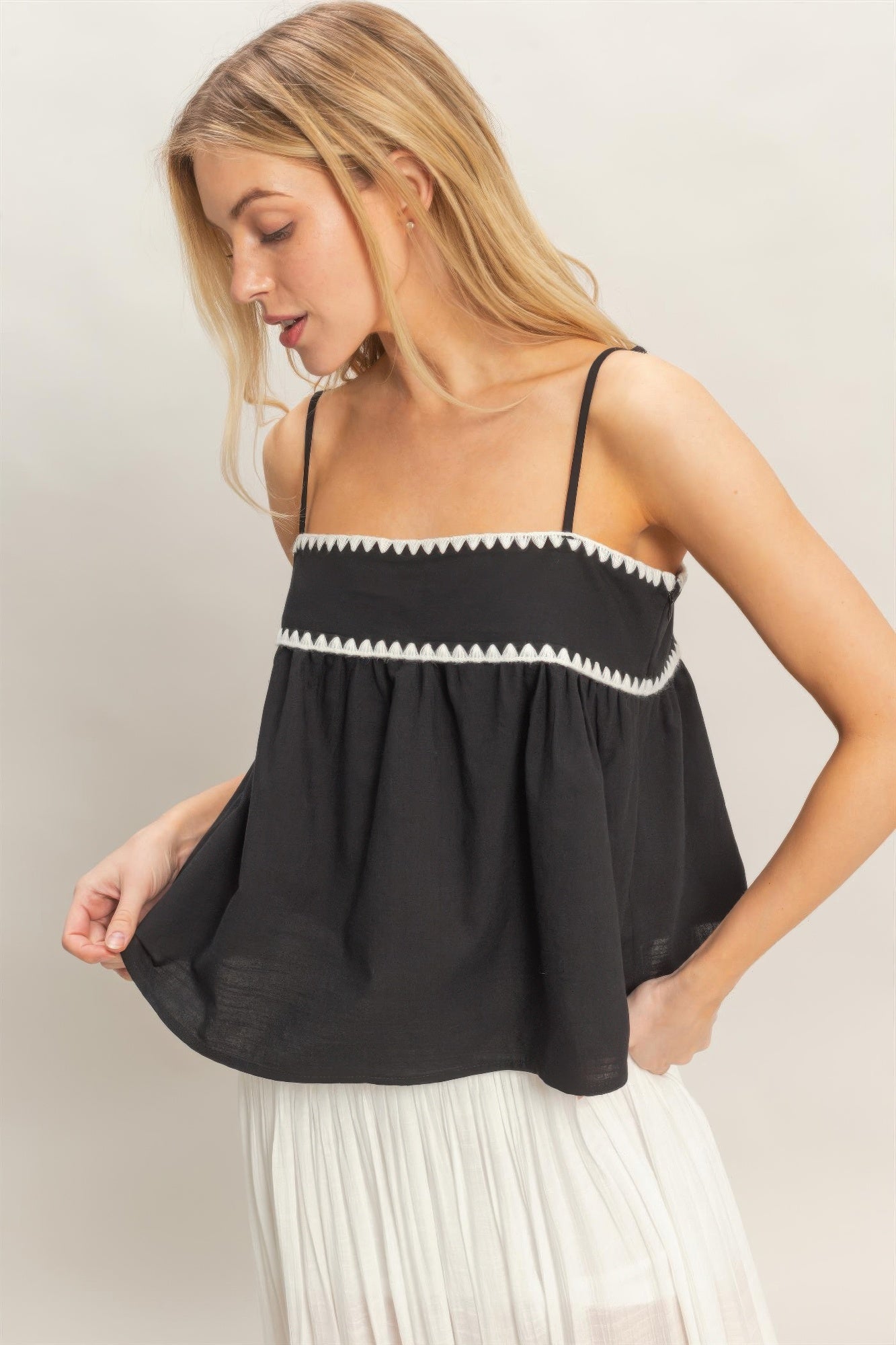 Black sleeveless babydoll top with white trim band and gathered, flowing shape
