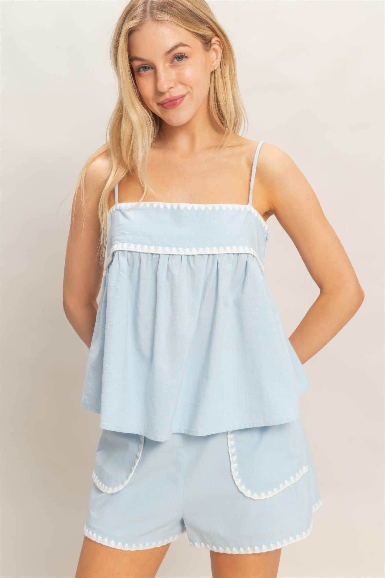 Sleeveless babydoll top in light blue with scalloped/zigzag trim across bust
