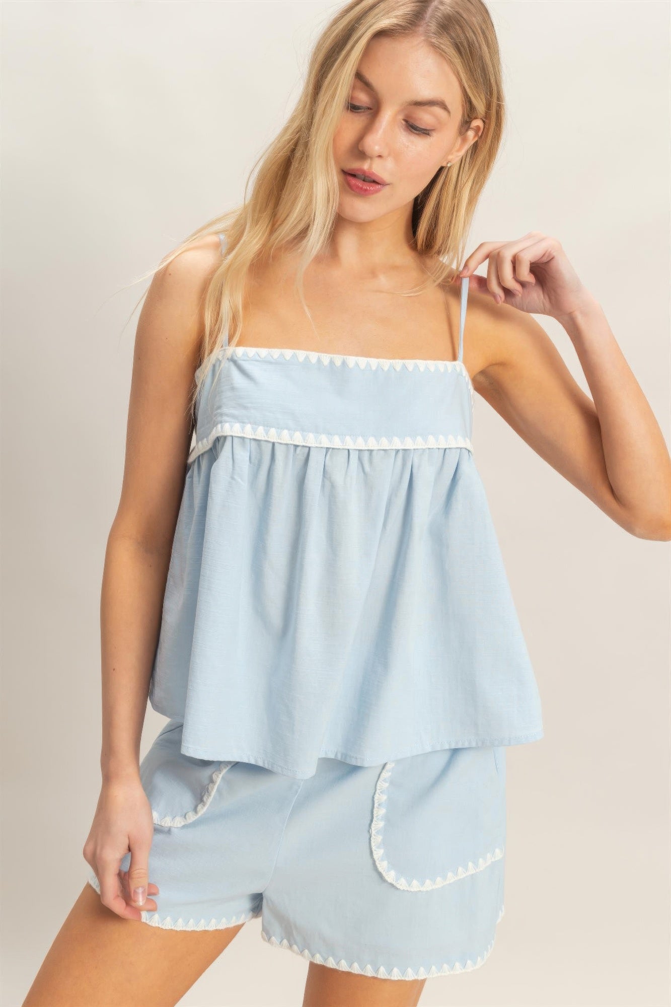 Light blue sleeveless babydoll top with thin straps and ruffled, tiered silhouette