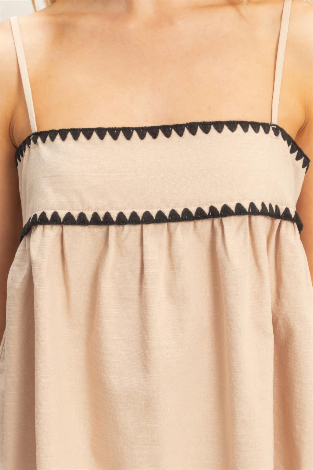 Beige babydoll top close-up: black striped trim across bust and ruffled yoke