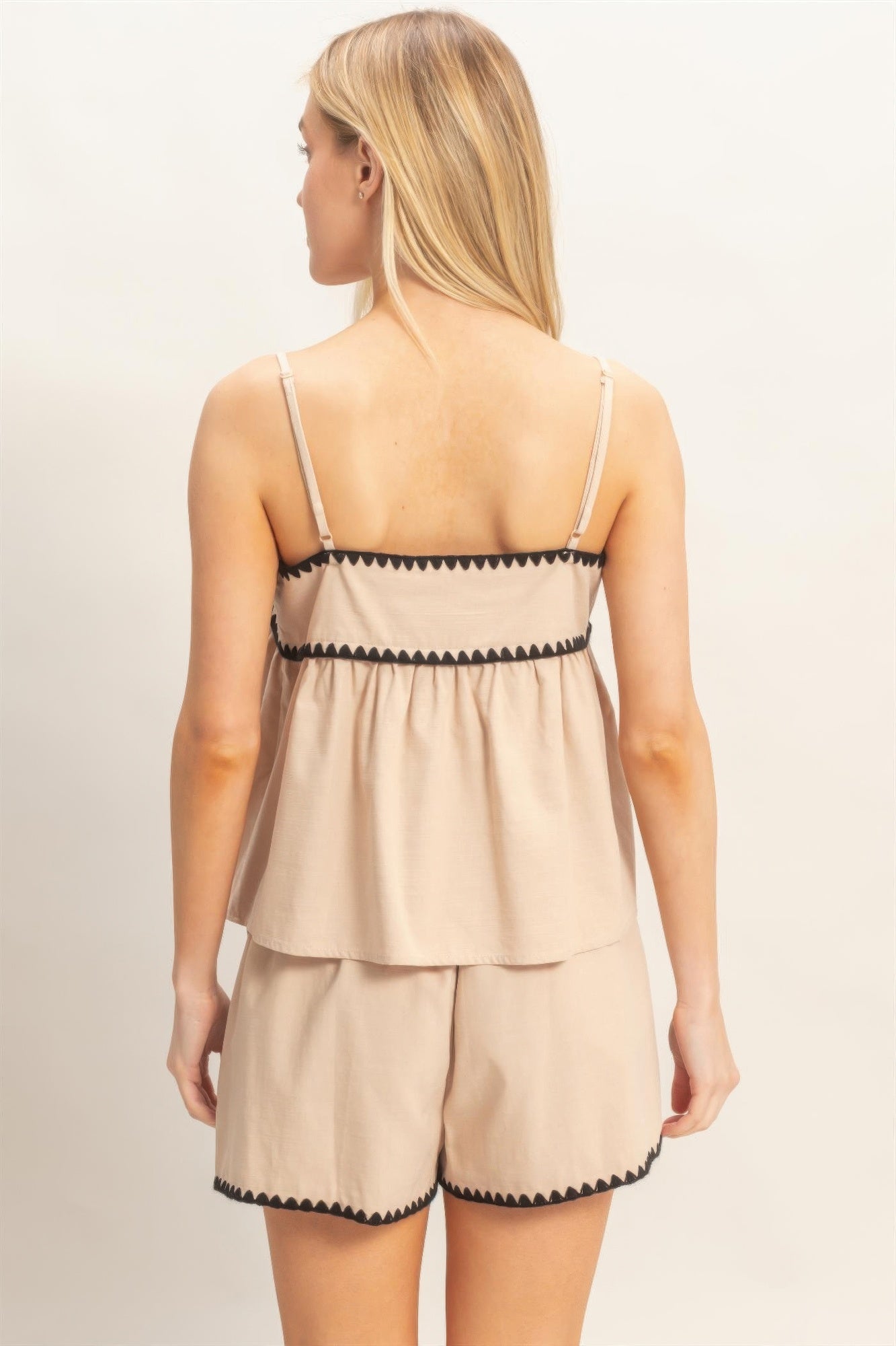 Beige babydoll top back: thin straps and scalloped black trim at waist