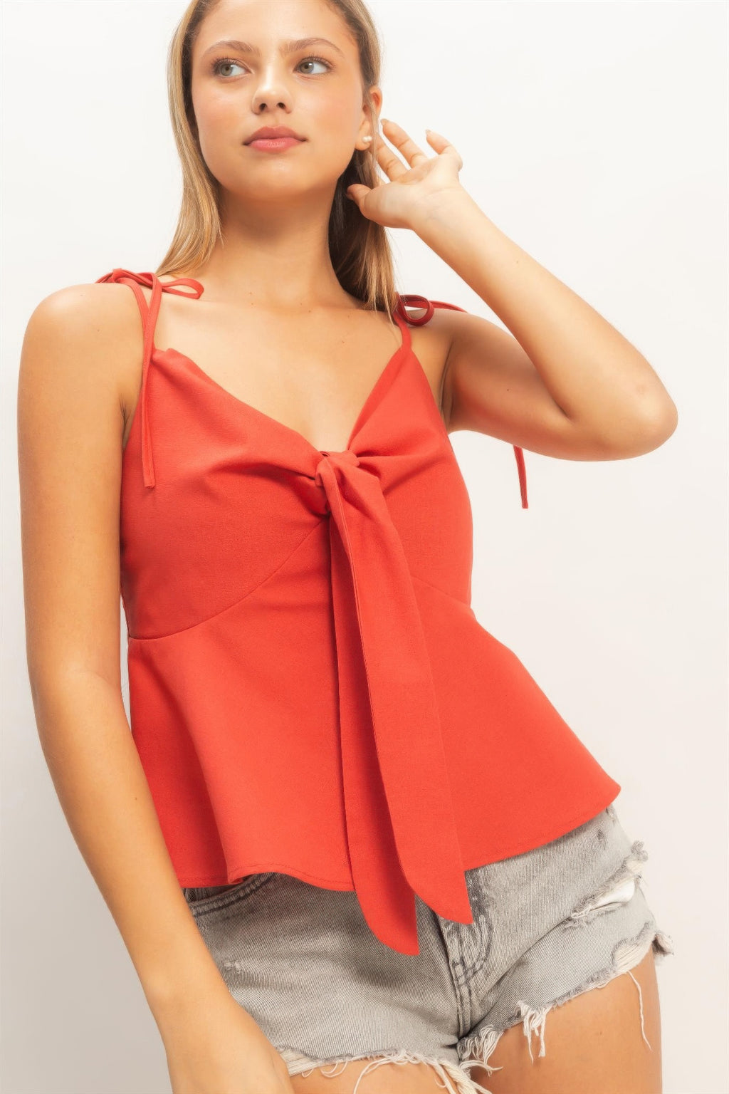 Close-up tomato red tie-front spaghetti strap peplum top with bow at bust