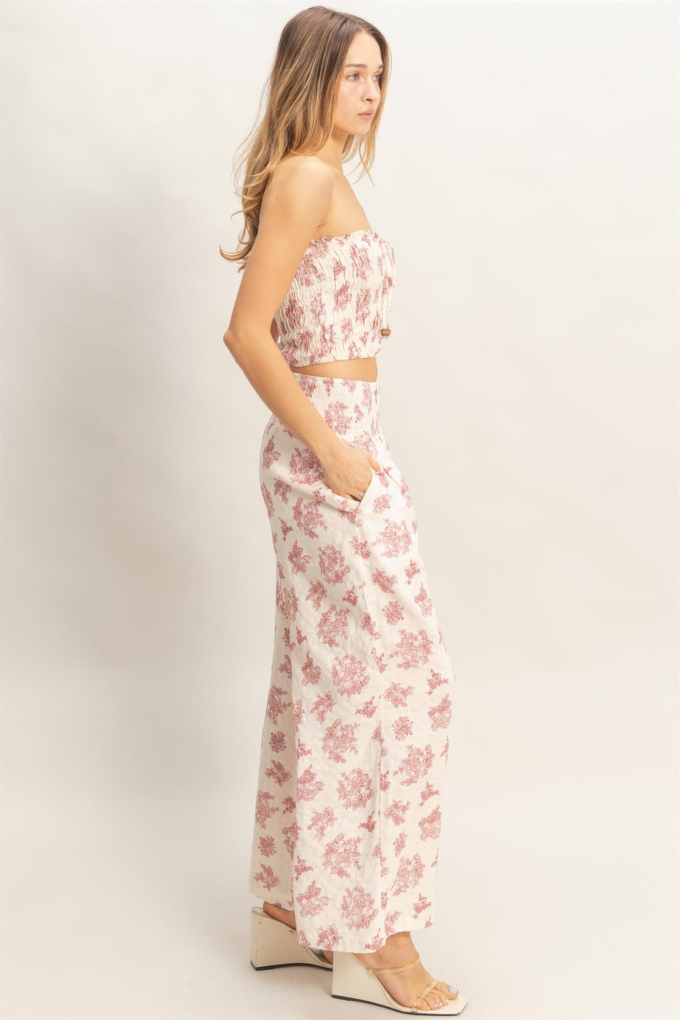 Side view of smocked tube top and wide-leg pants; light base with red floral print.