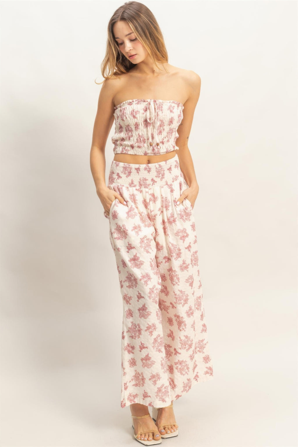 Front view of smocked tube top and wide-leg pants set; light base with red floral print.