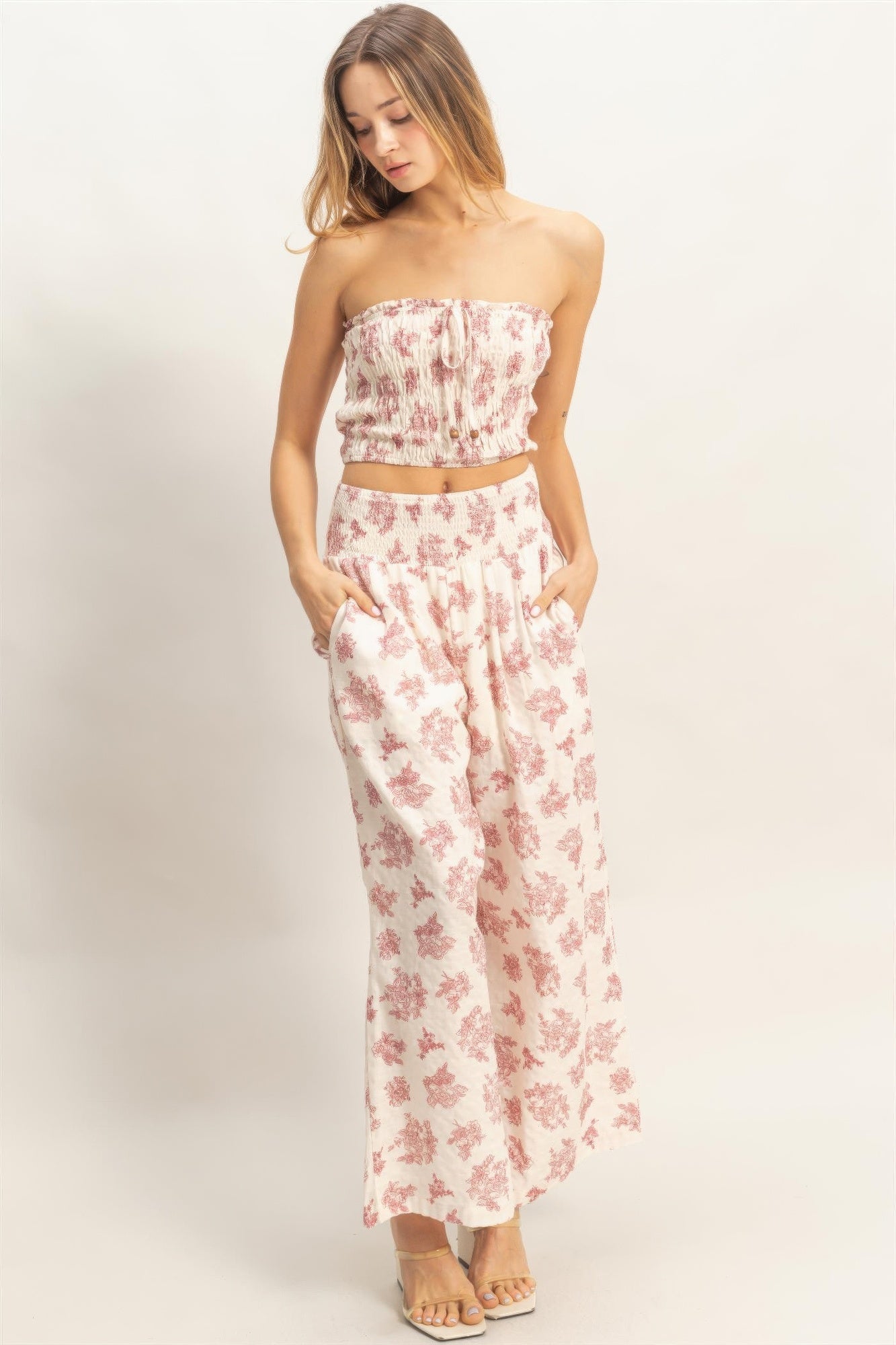 Front view of smocked tube top and wide-leg pants set; light base with red floral print.