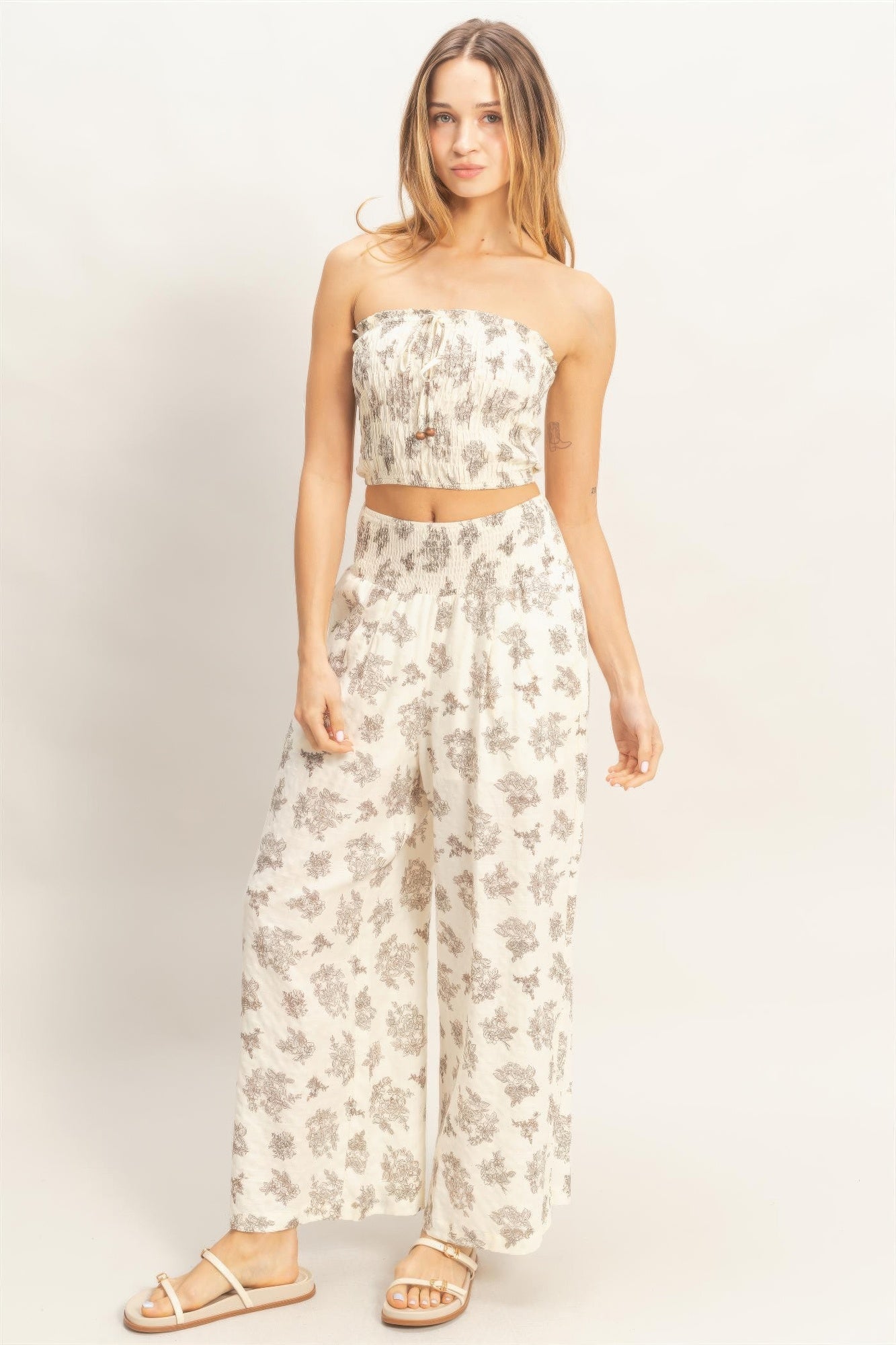 Smocked strapless tube top and wide-leg pants set, light base with gray floral print.