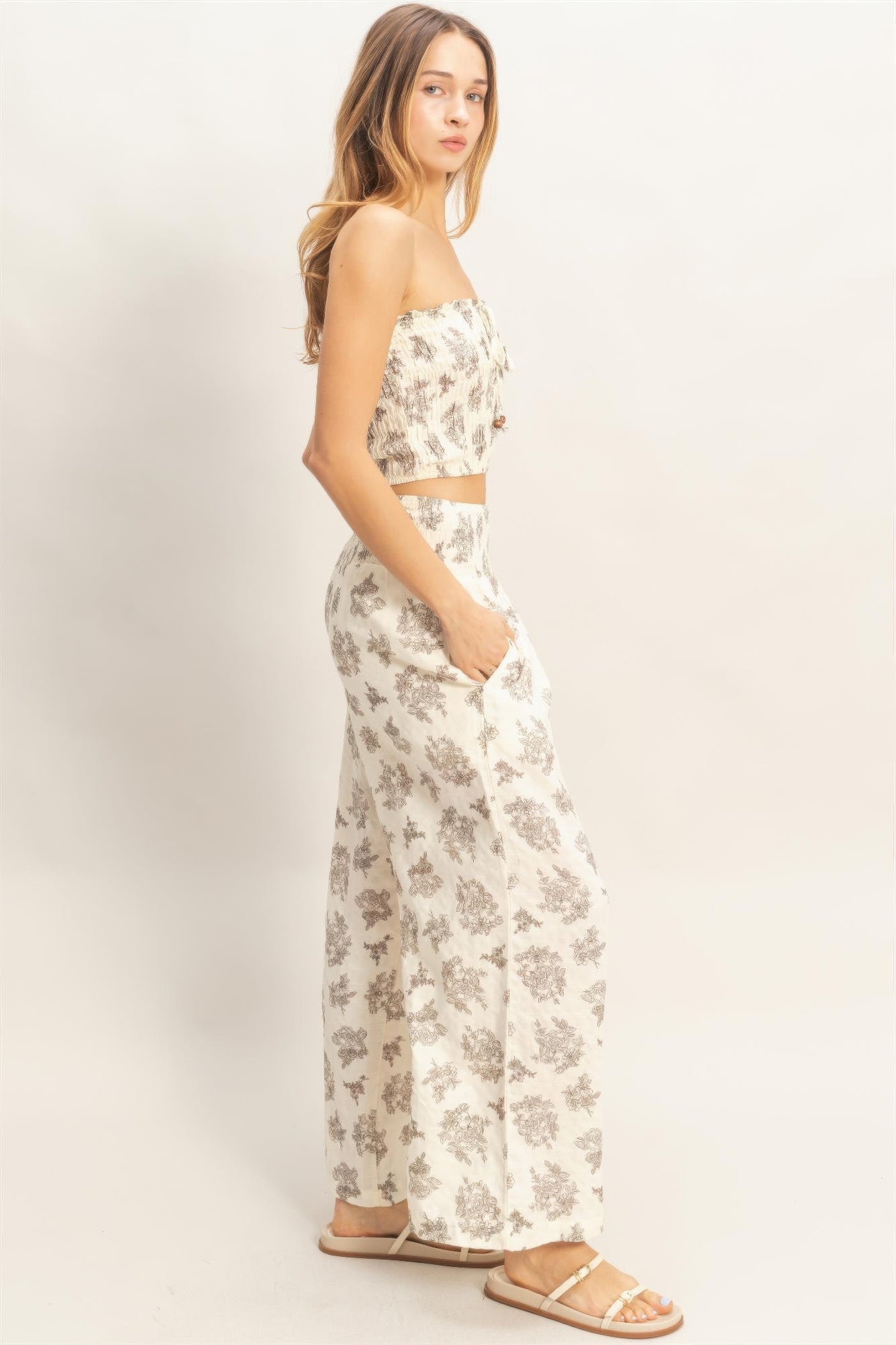 Wide-leg pants with smocked tube top, side view; light base with gray floral print.