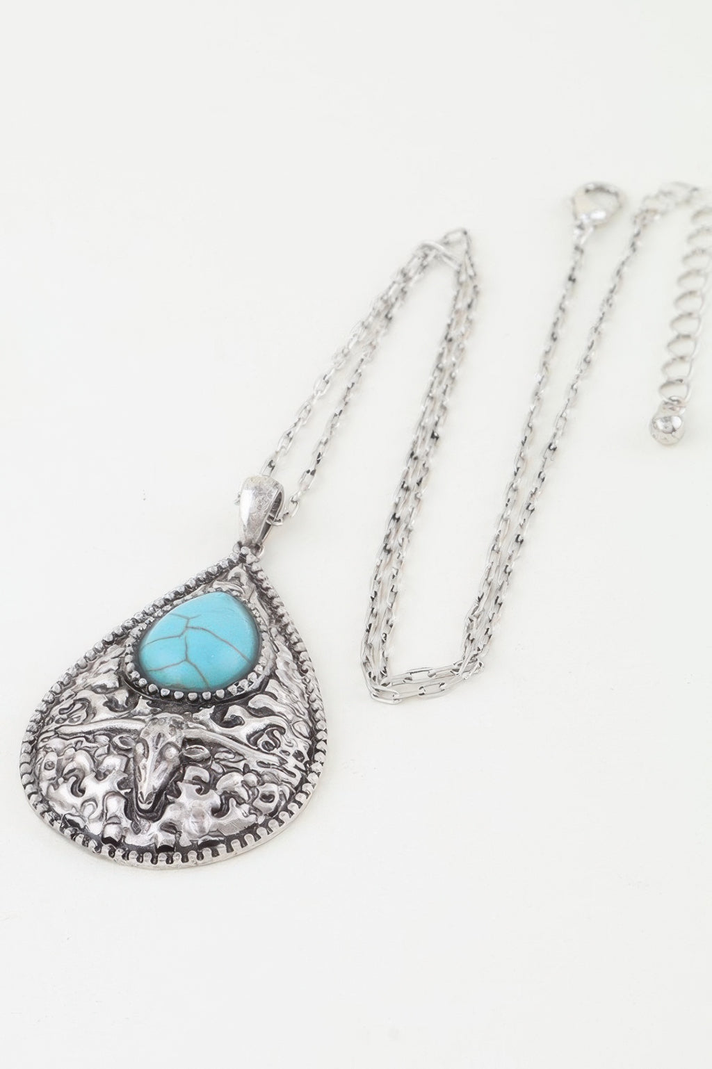 Turquoise bull teardrop necklace pendant on chain, ornate silver filigree side view
